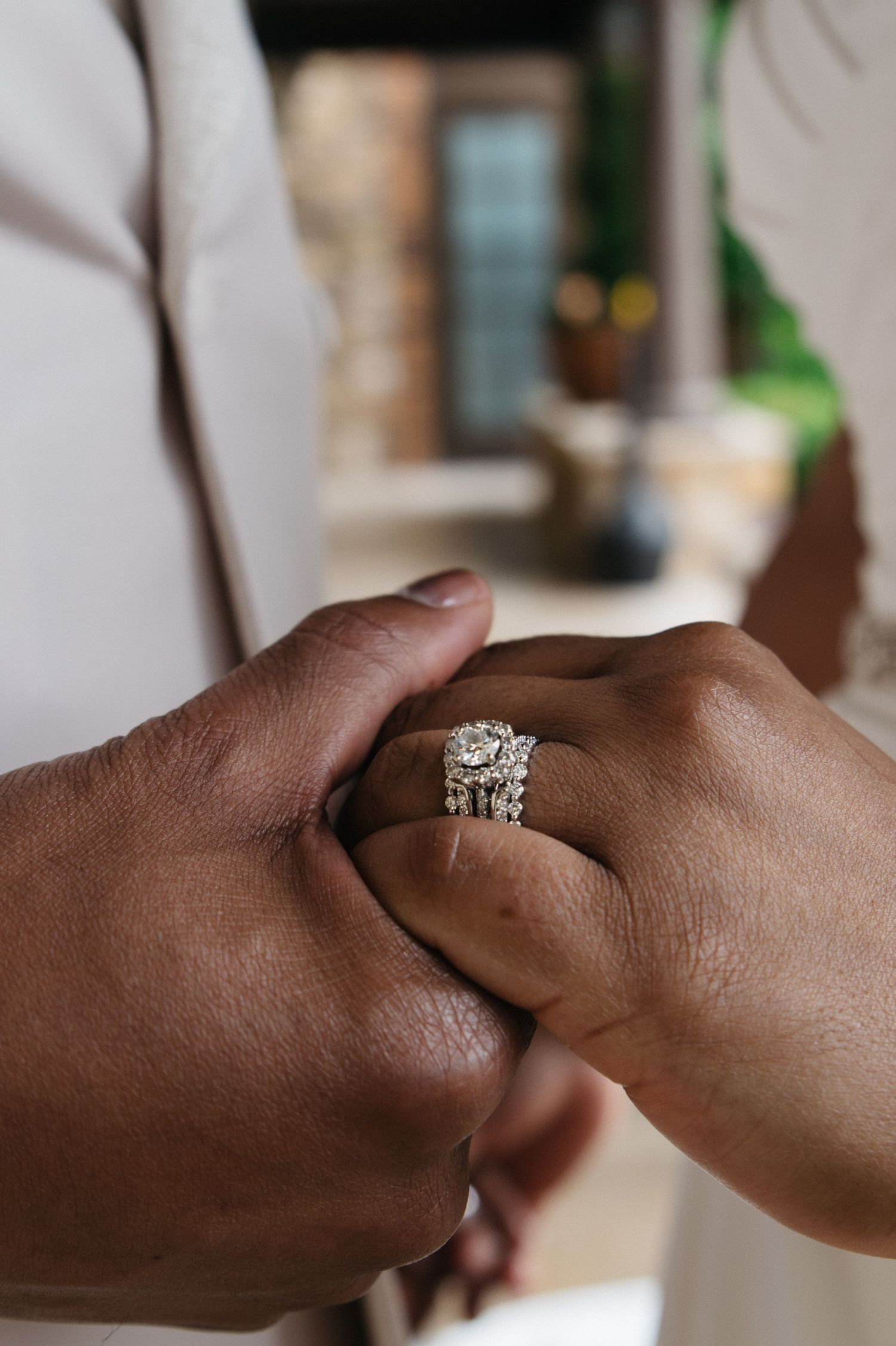 Close-up of two hands holding, showcasing a stunning diamond engagement ring and wedding band set.