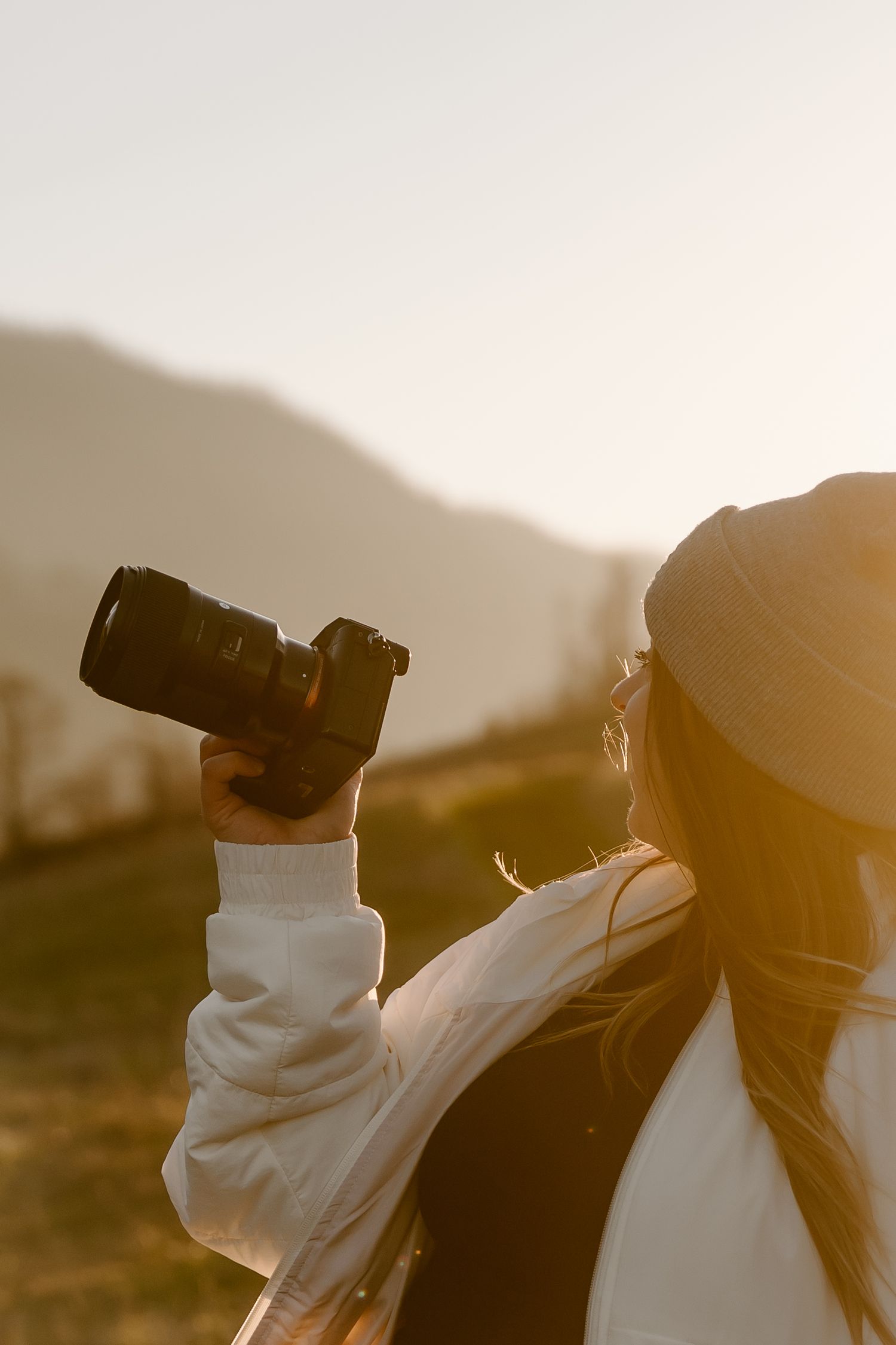 Silhouette of two people wearing masks and holding cameras against a golden sunset backdrop.