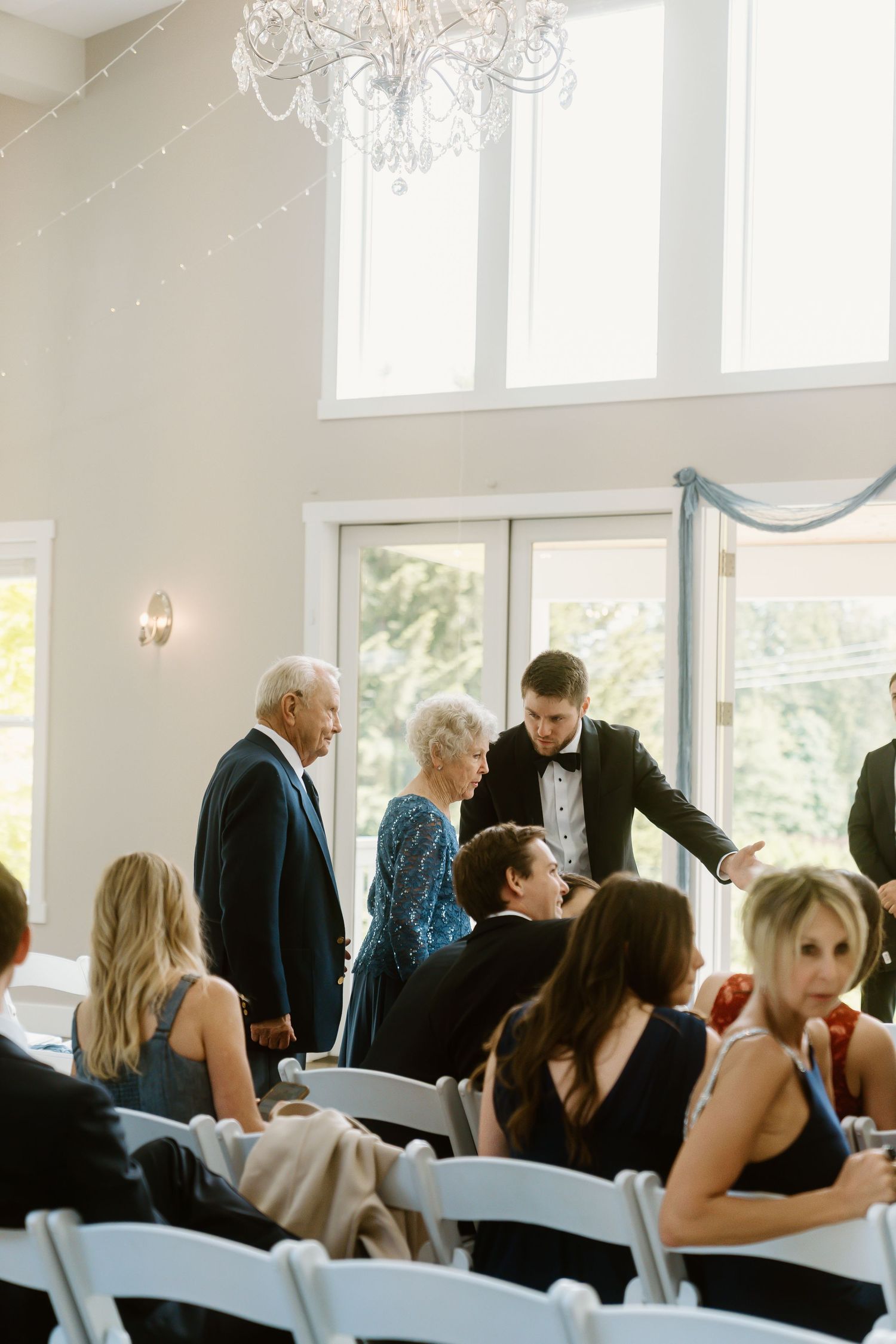 Wedding guests being escorted to their seats in a bright elegant ceremony venue.