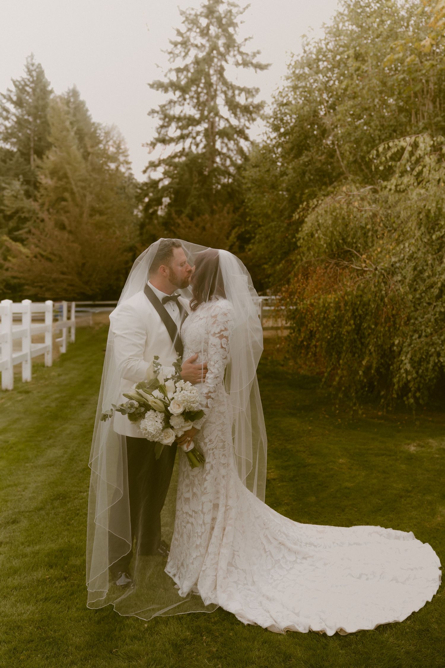 A romantic outdoor wedding photoshoot with white picket fence and lush greenery.