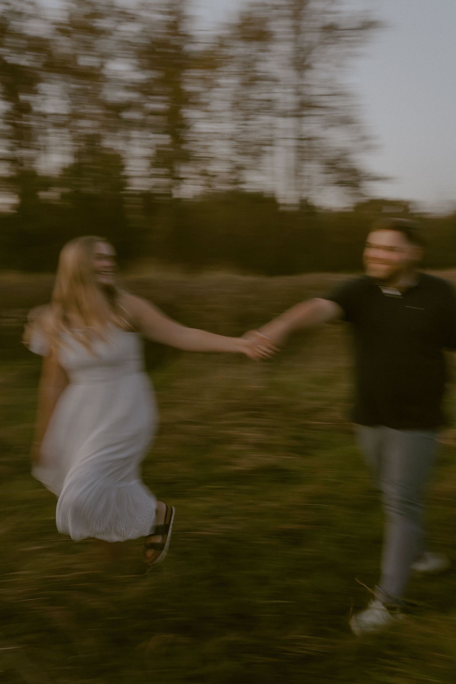 Artistic motion blur captures a couple dancing in a field at dusk.