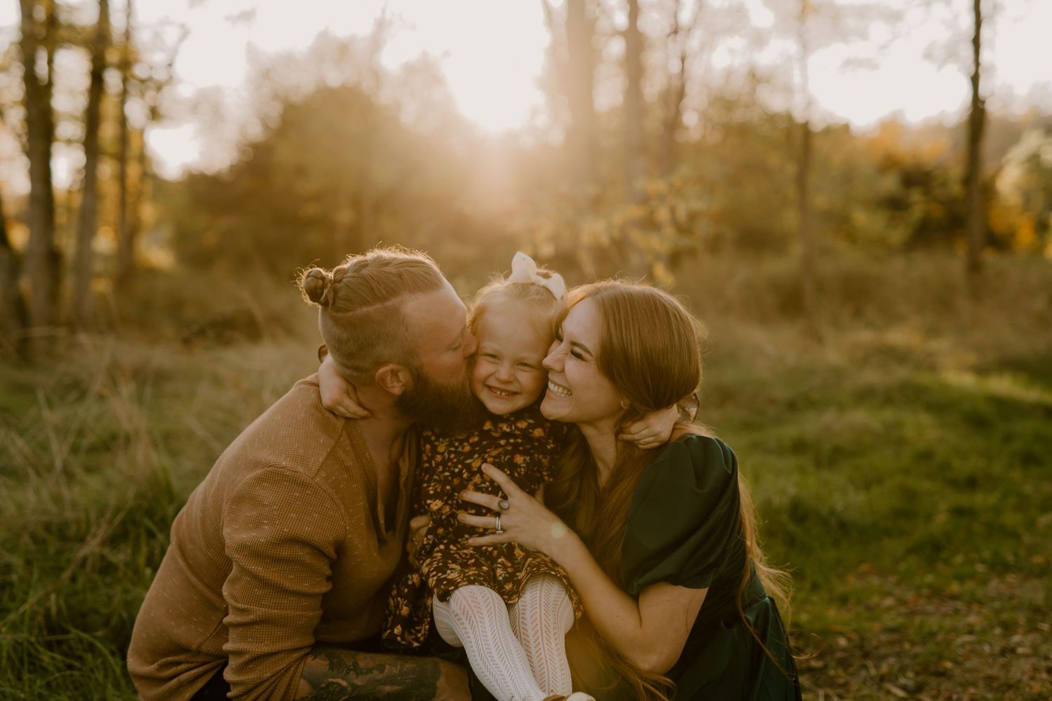 A couple shares an intimate moment in a sun-drenched forest during a golden hour photoshoot.