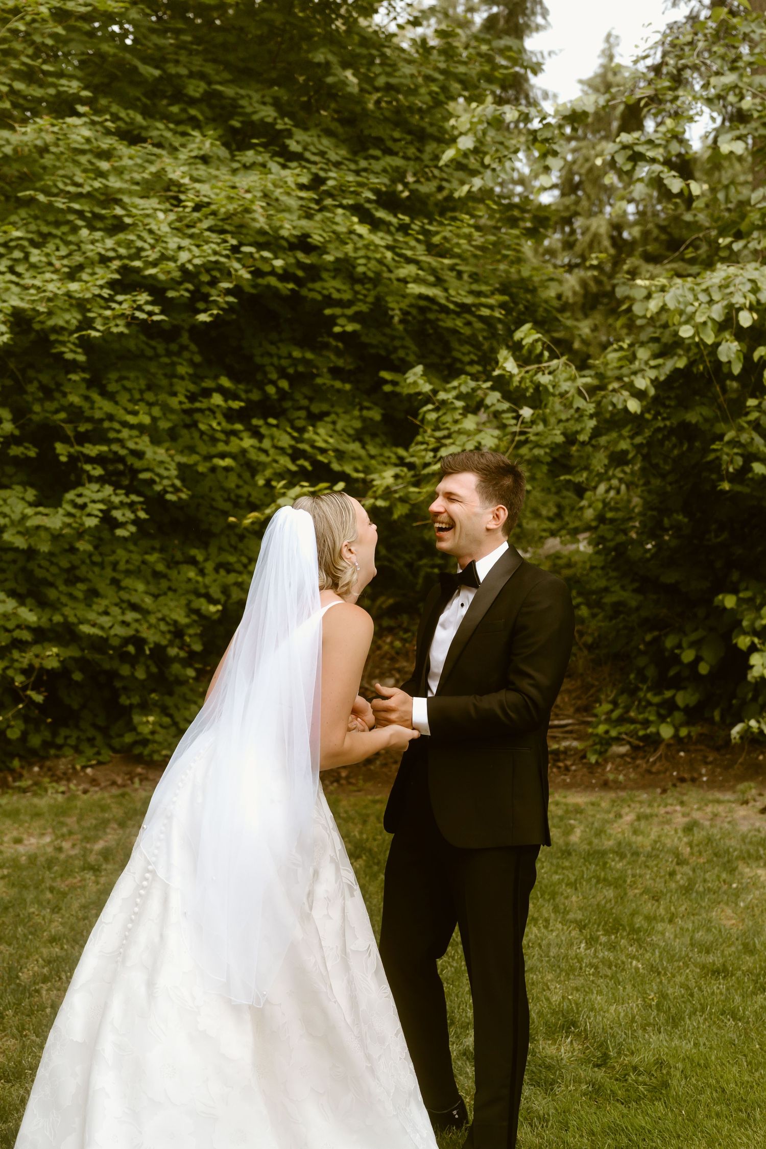Bride and groom sharing a joyful first look moment on a lush green lawn.