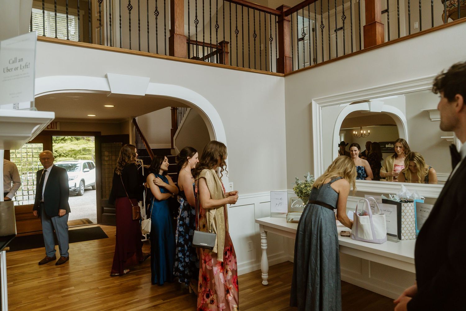 Wedding guests mingle in elegant venue foyer with arched doorways and second floor balcony.