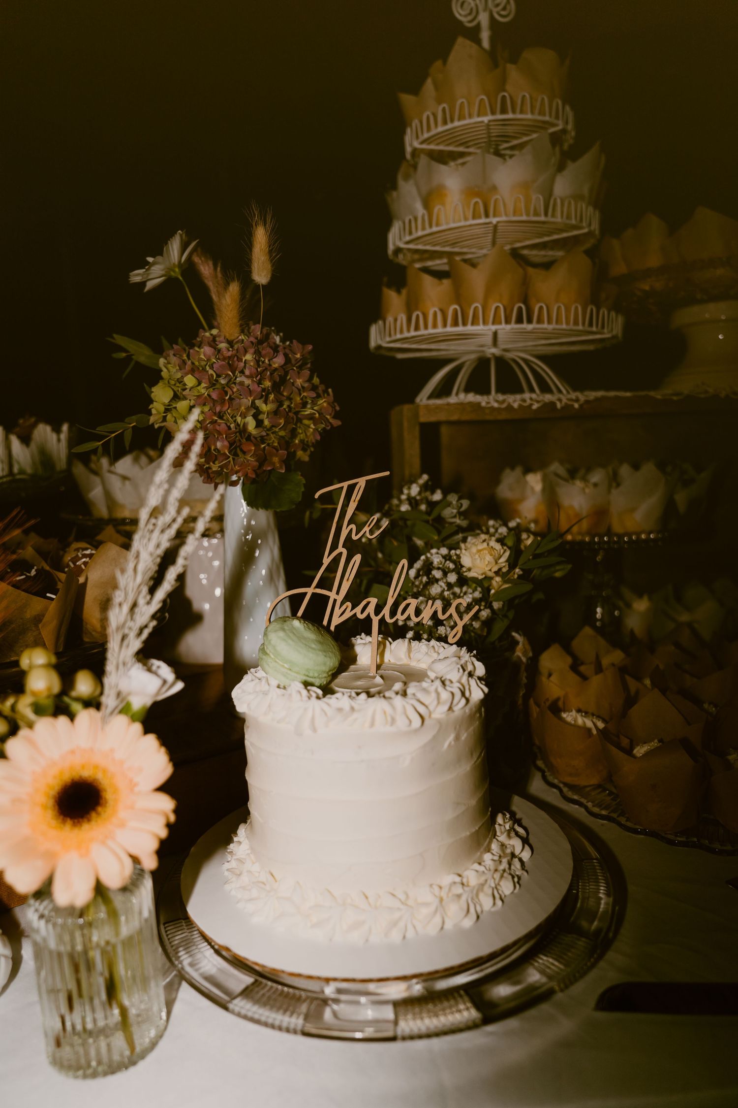 A series of elegant white wedding cakes with floral decorations and cake toppers displayed on vintage cake stands.