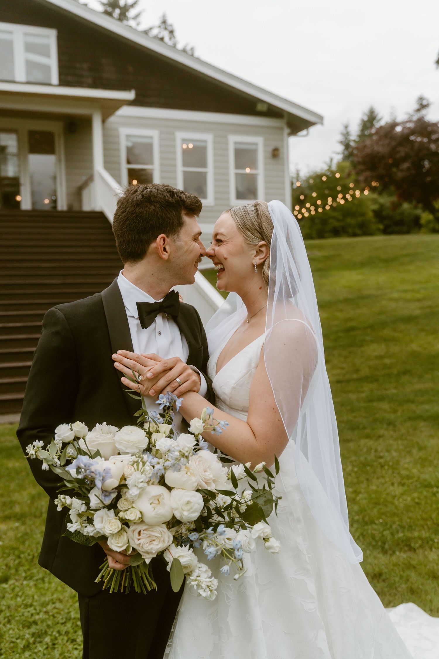 Bride and groom sharing an intimate moment outdoors, bride holding white and blue floral bouquet.