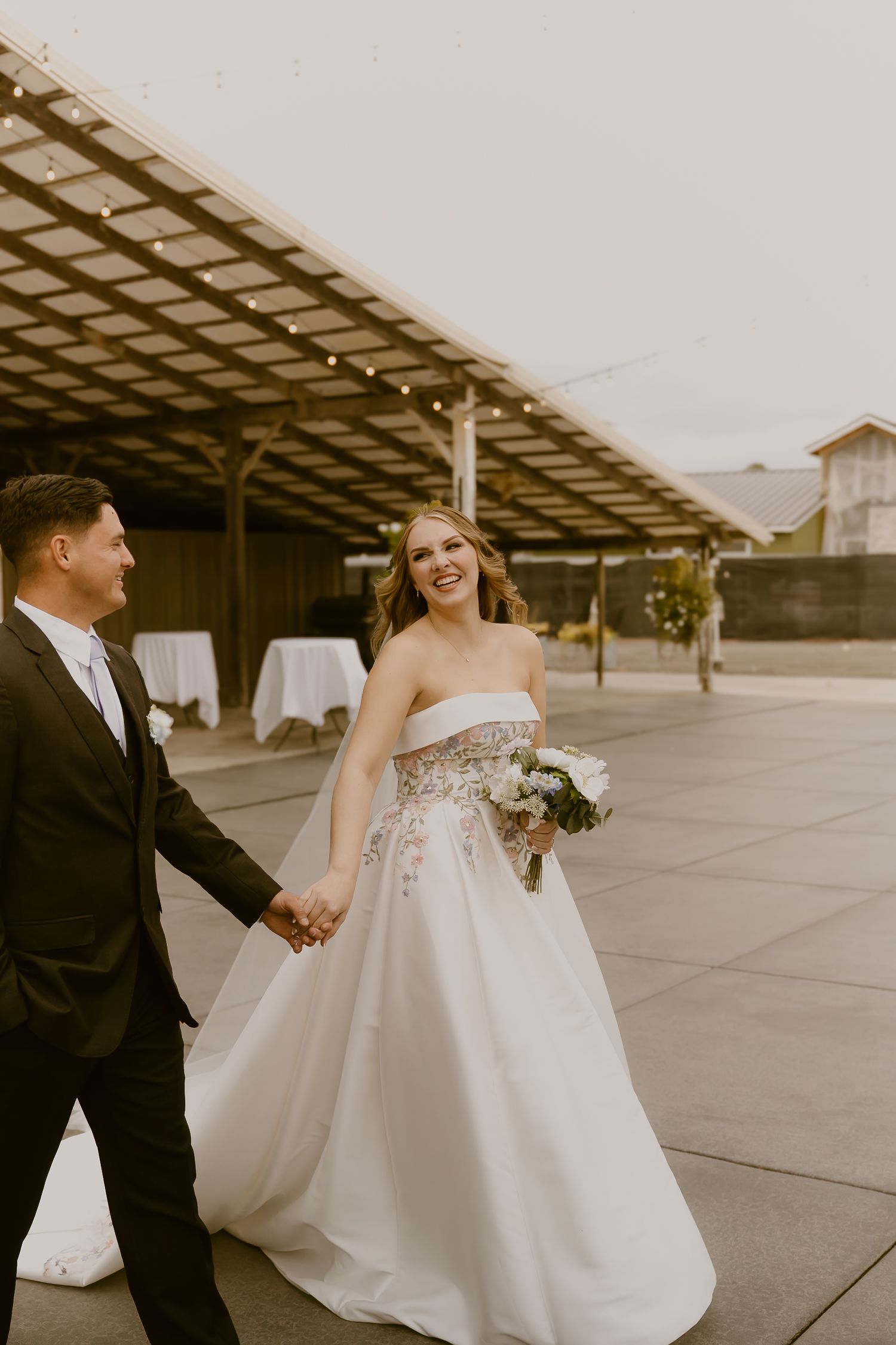 A romantic wedding couple shares a joyful moment together on an industrial rooftop with geometric architectural details.