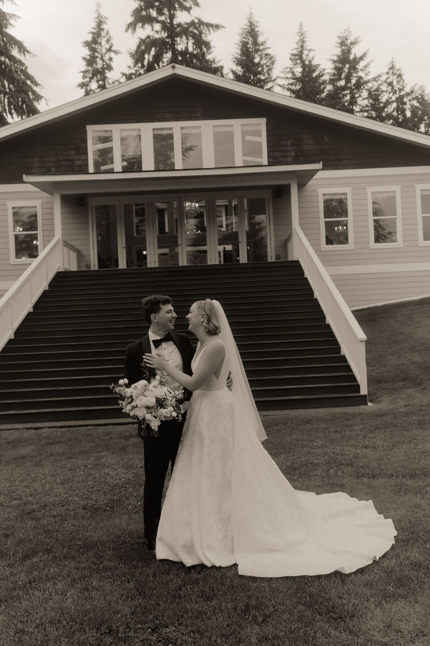 Bride and groom share a romantic moment in black and white photo outside their wedding venue.