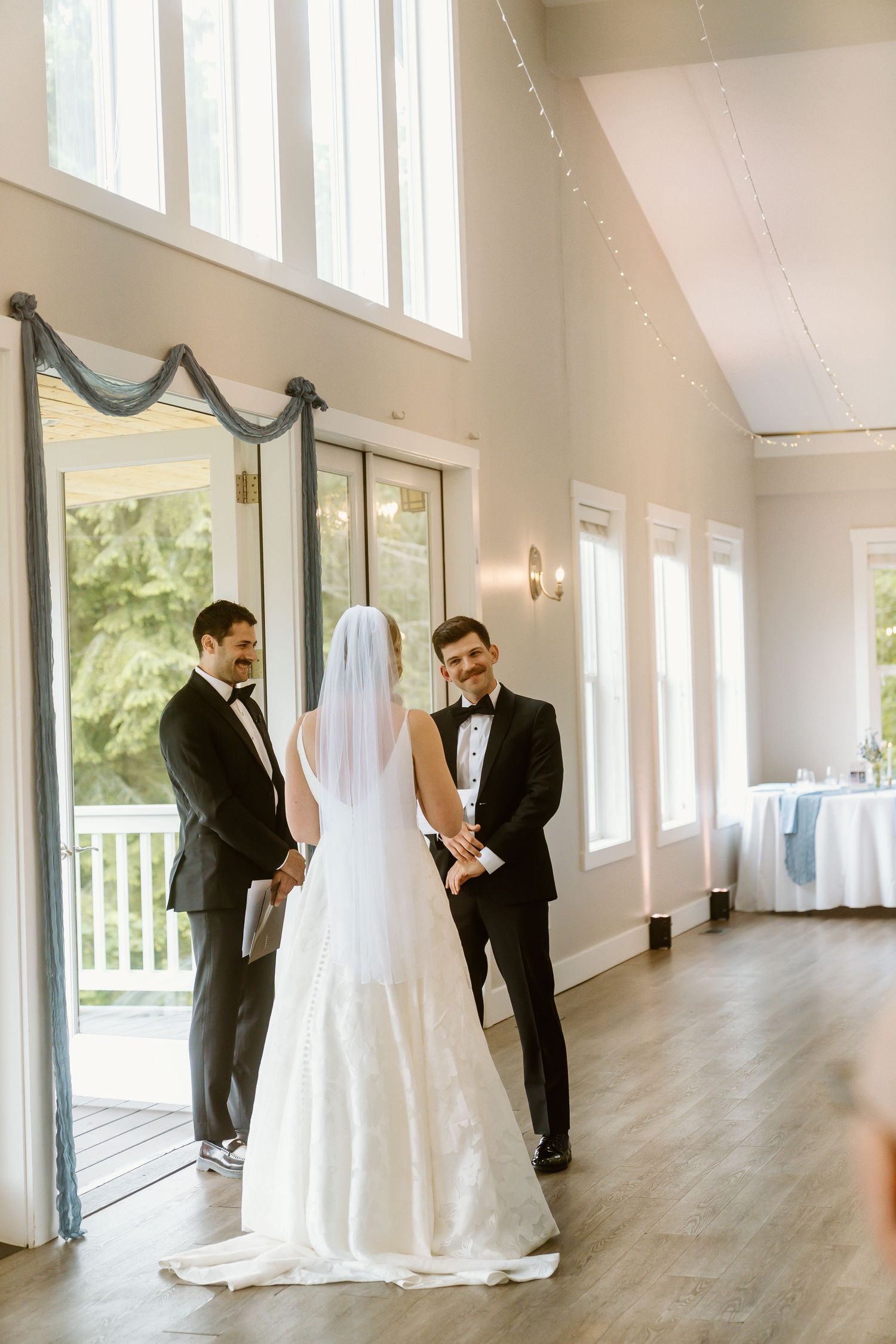 Bride and groom exchange vows at the altar with an officiant in a bright indoor wedding venue.