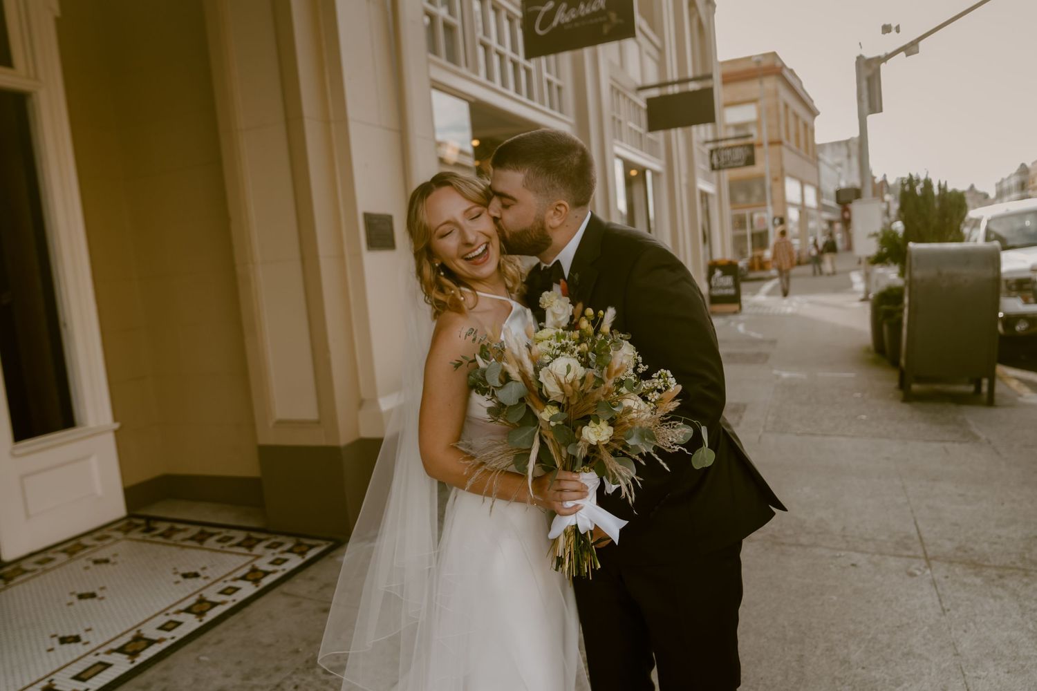 A romantic wedding couple embraces in a series of candid black and white photos on a city street.