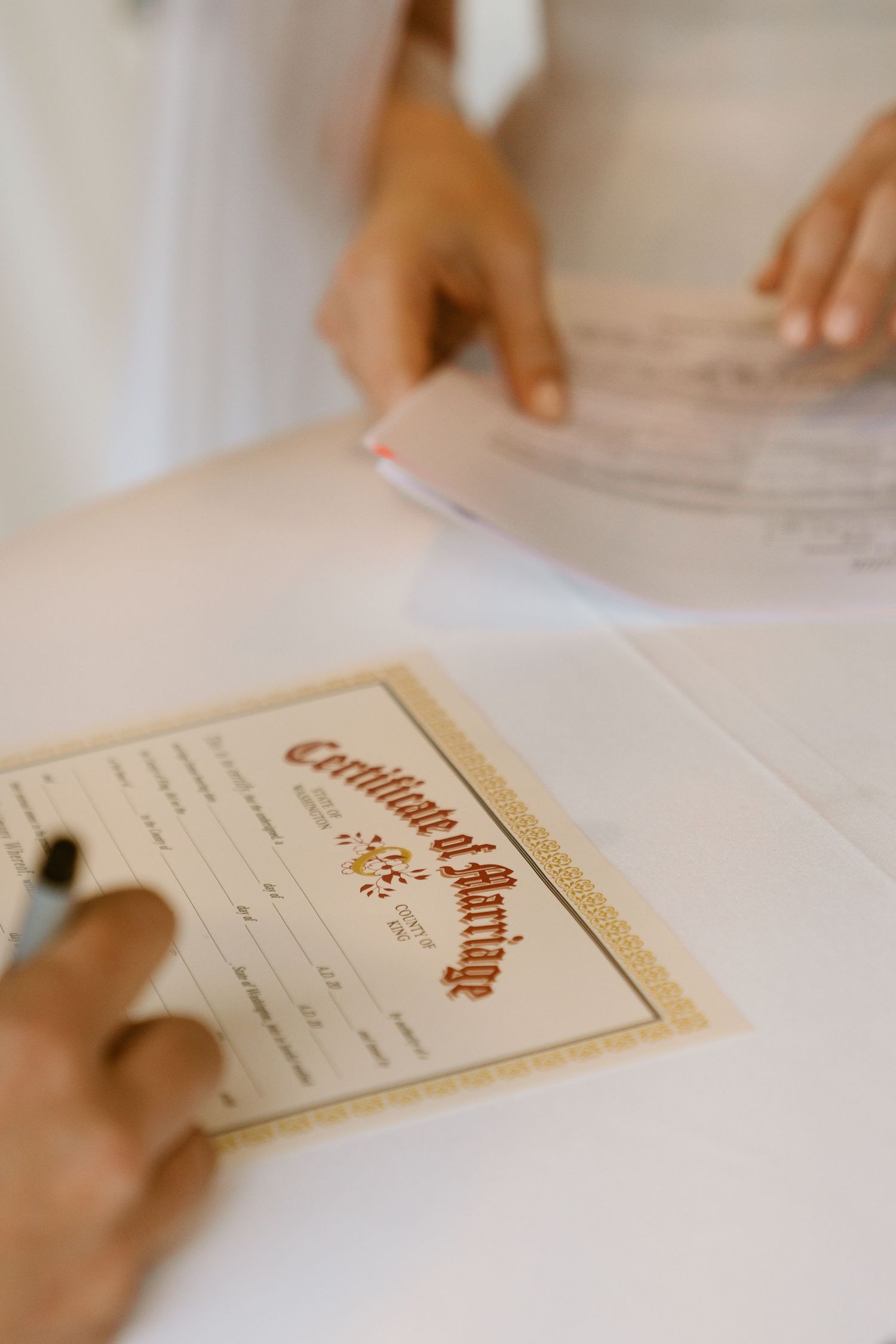 Close-up of a Certificate of Marriage being signed at a wedding ceremony table.