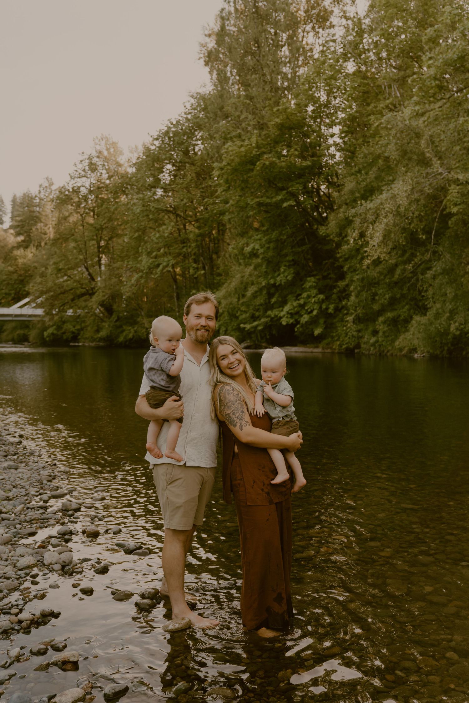 Family sharing joyful moments and embraces along the rocky shoreline of a tranquil lake.