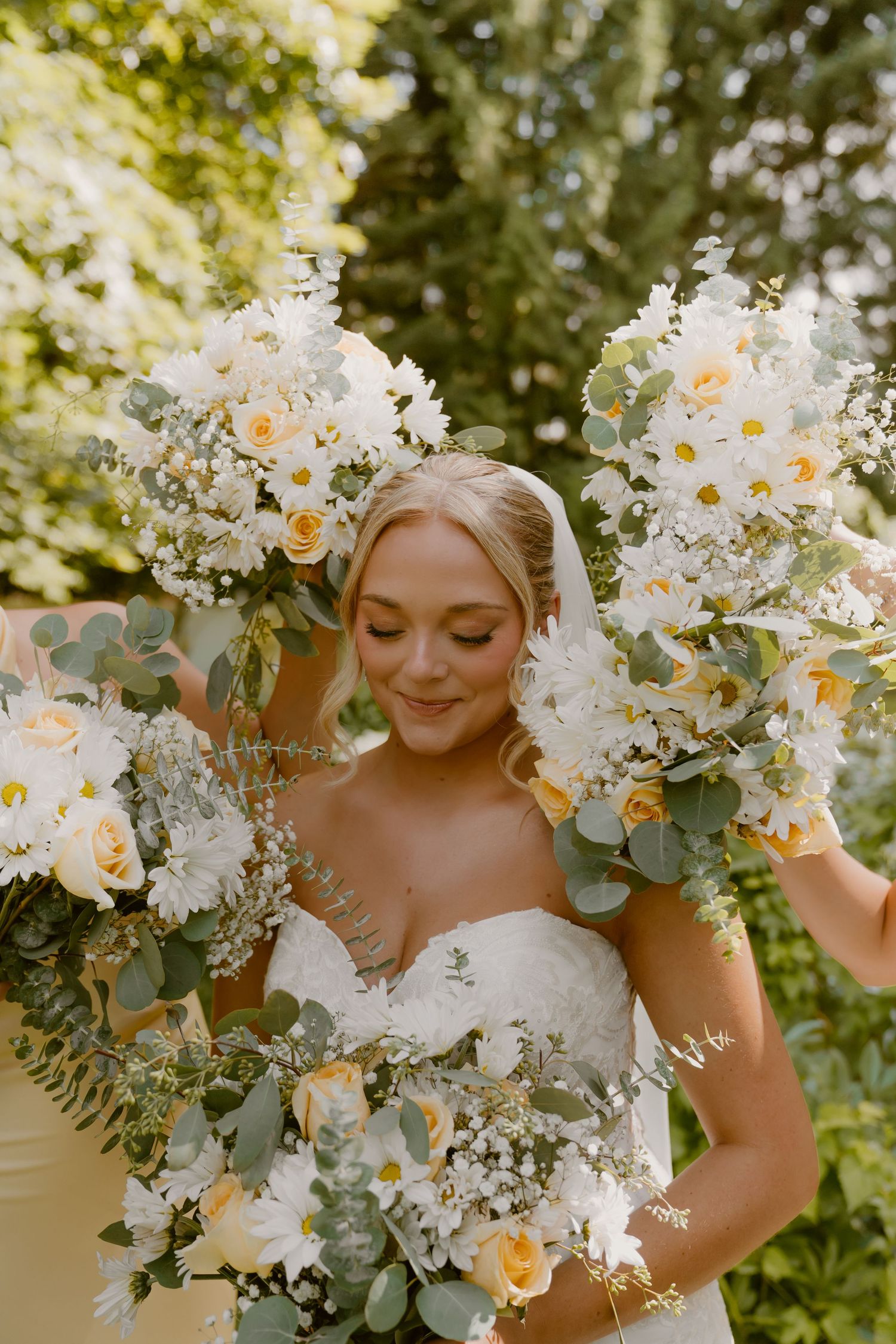 A beautiful white and yellow floral wedding bouquet arrangement with eucalyptus leaves in a natural outdoor setting.