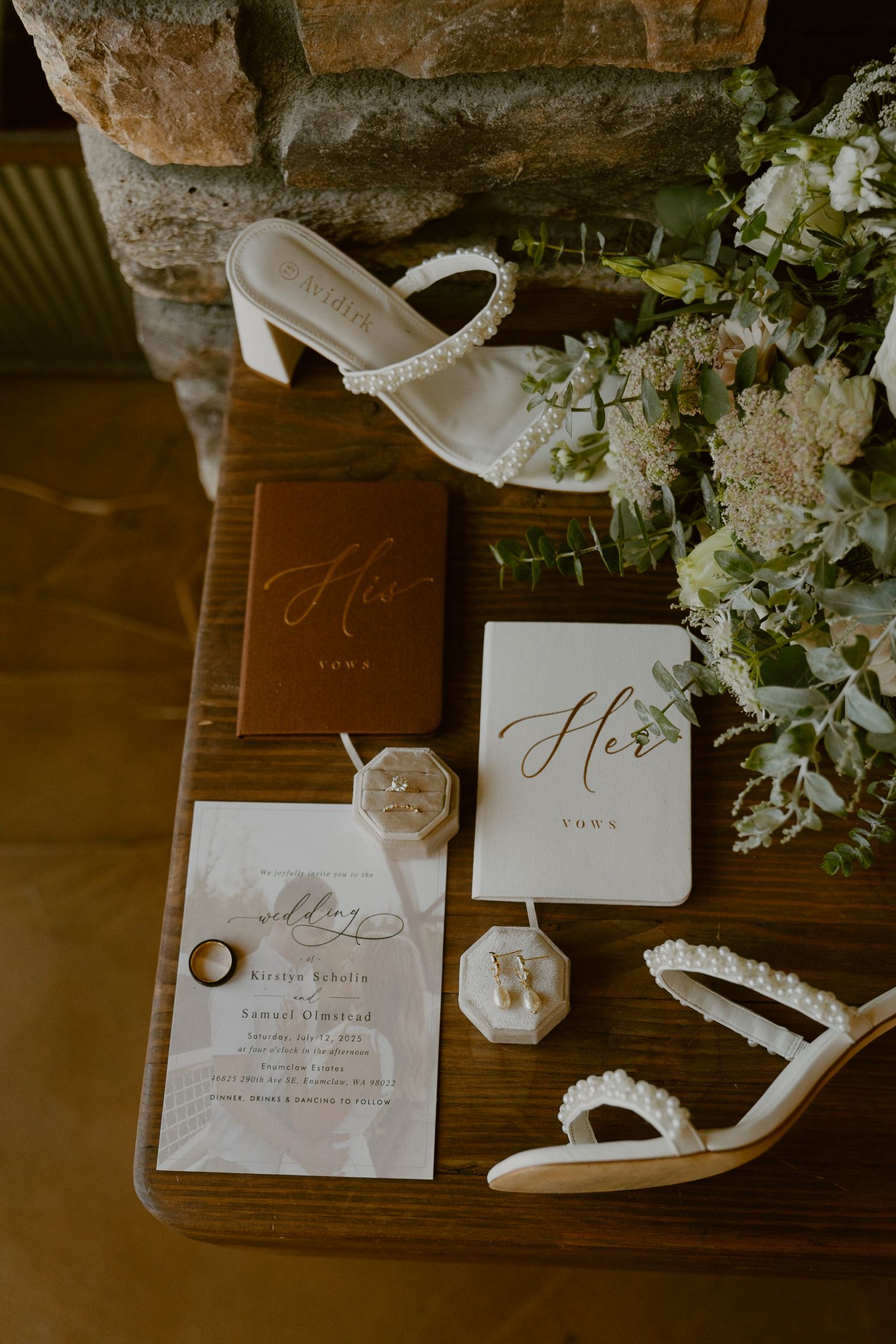 Wedding details including white floral arrangements, elegant stationery, and delicate accessories on a rustic wooden surface.
