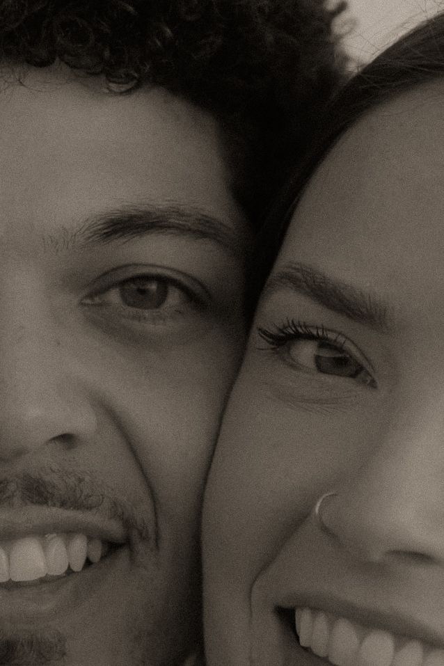 Black and white close-up portrait of a smiling couple with heads together, showing joy and connection.