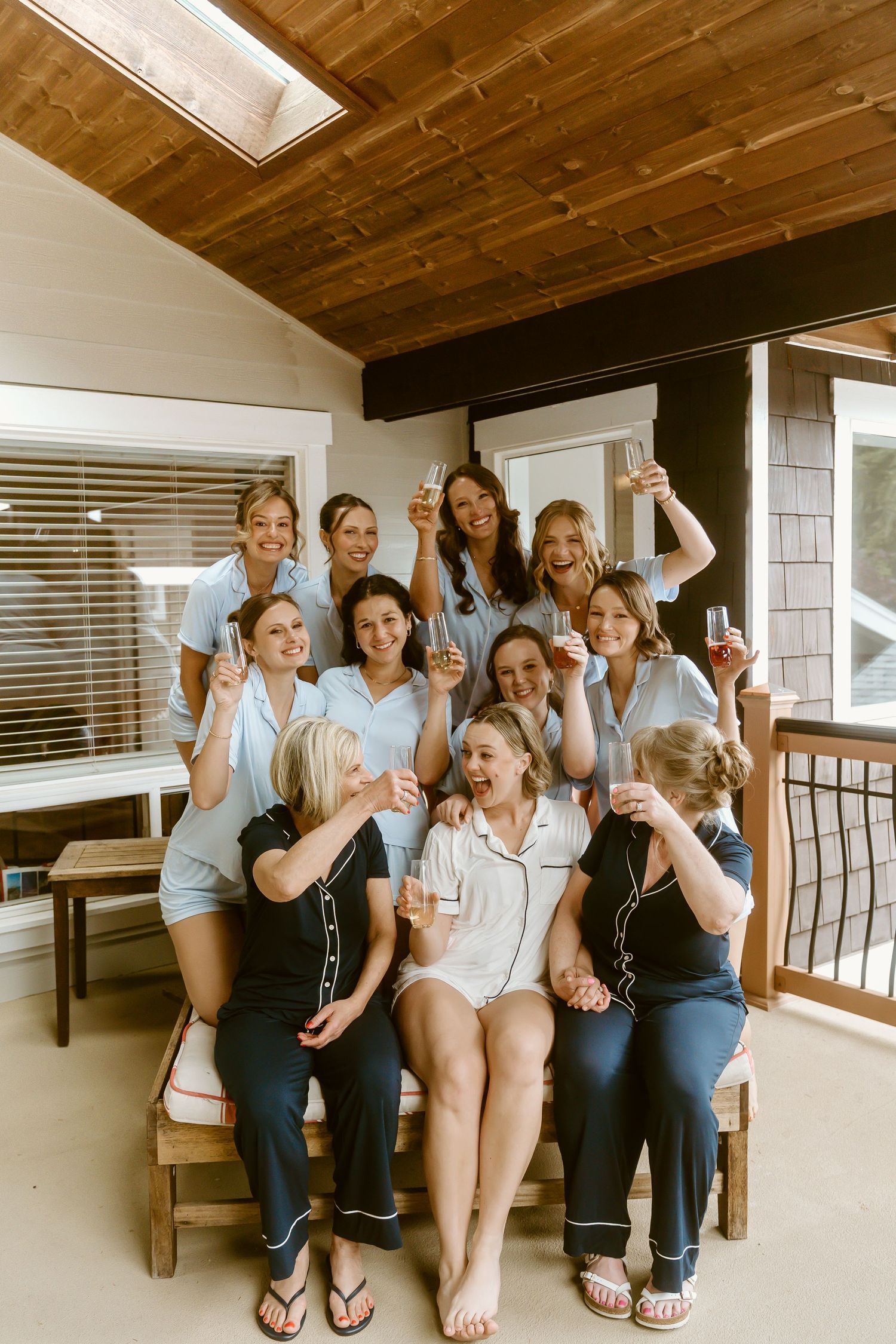 Group of bridesmaids in matching blue pajamas celebrating with champagne glasses during a bridal party getting ready session.