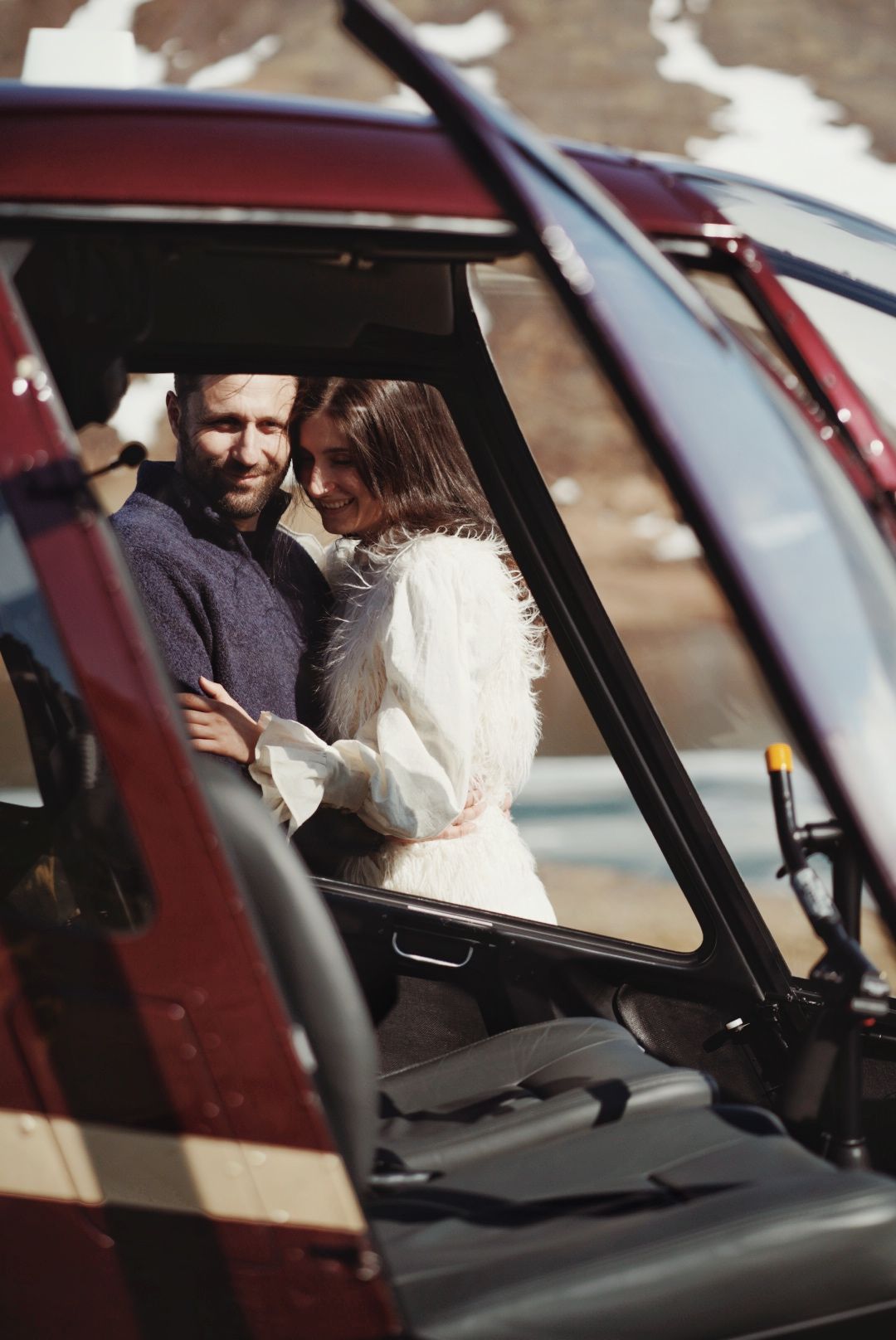 Interior view of a helicopter cockpit with the elopement couple visible through the windshield in Hvalfjörður Iceland