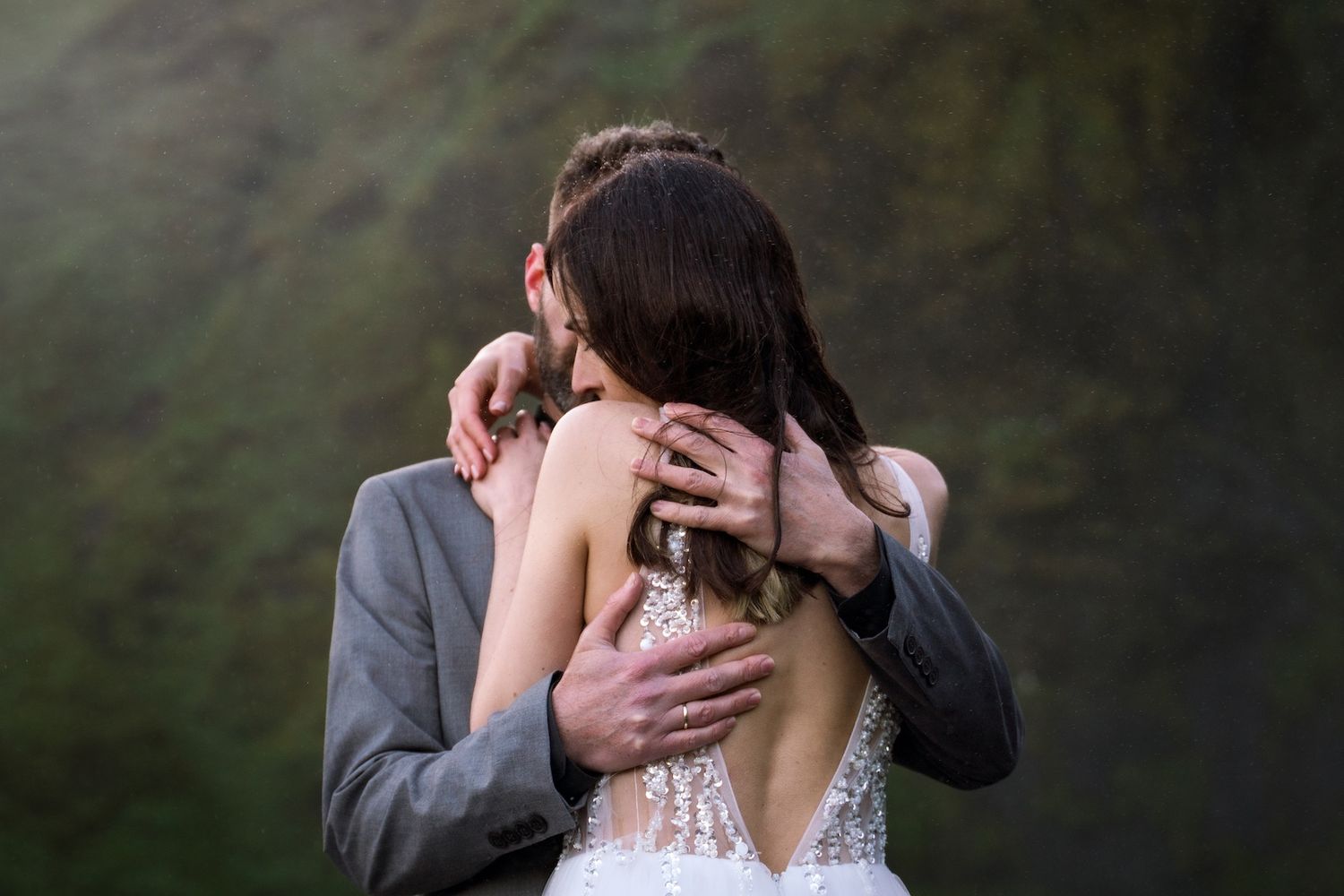 Couple hugging close in waterfall mist