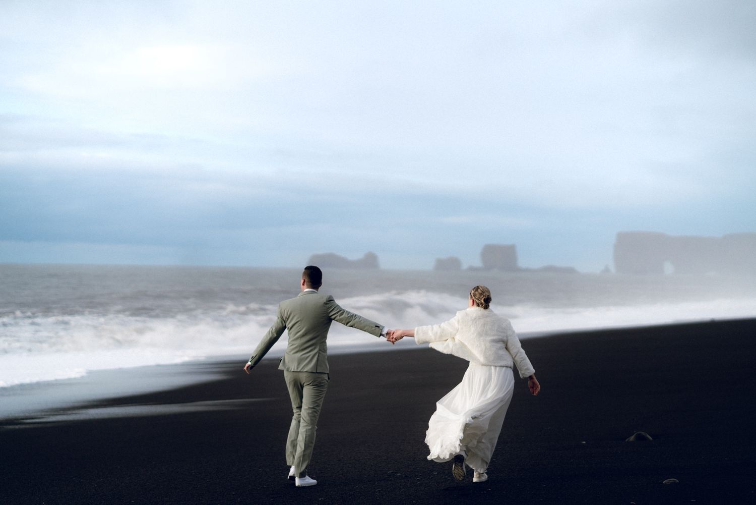 Elopement photo sessions in Iceland along the misty coastline of Reynisfjara Black Sand Beach with dramatic waves