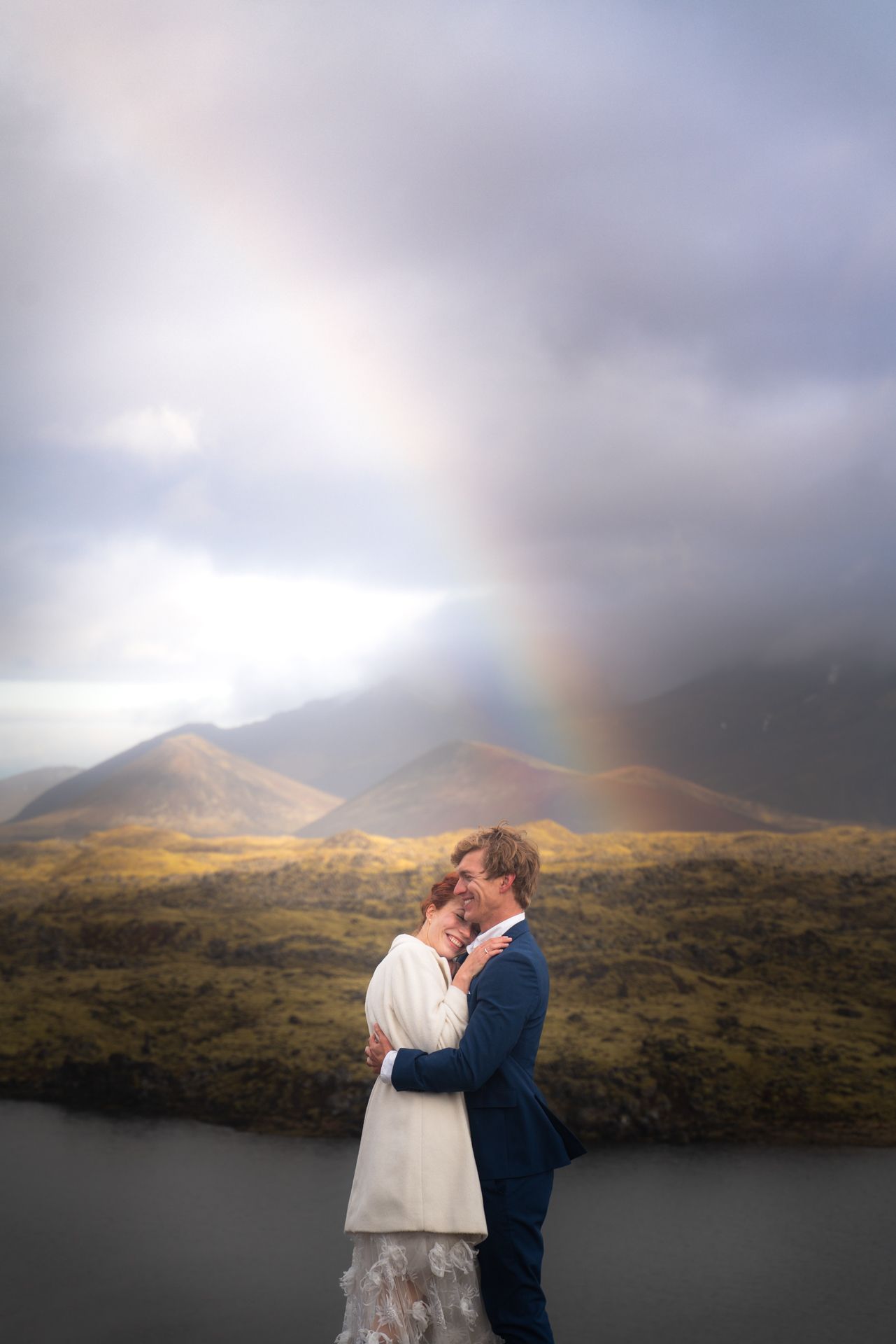 Elopement couple on Snæfellsnes Peninsula in Iceland under a rainbow with mountains in the background