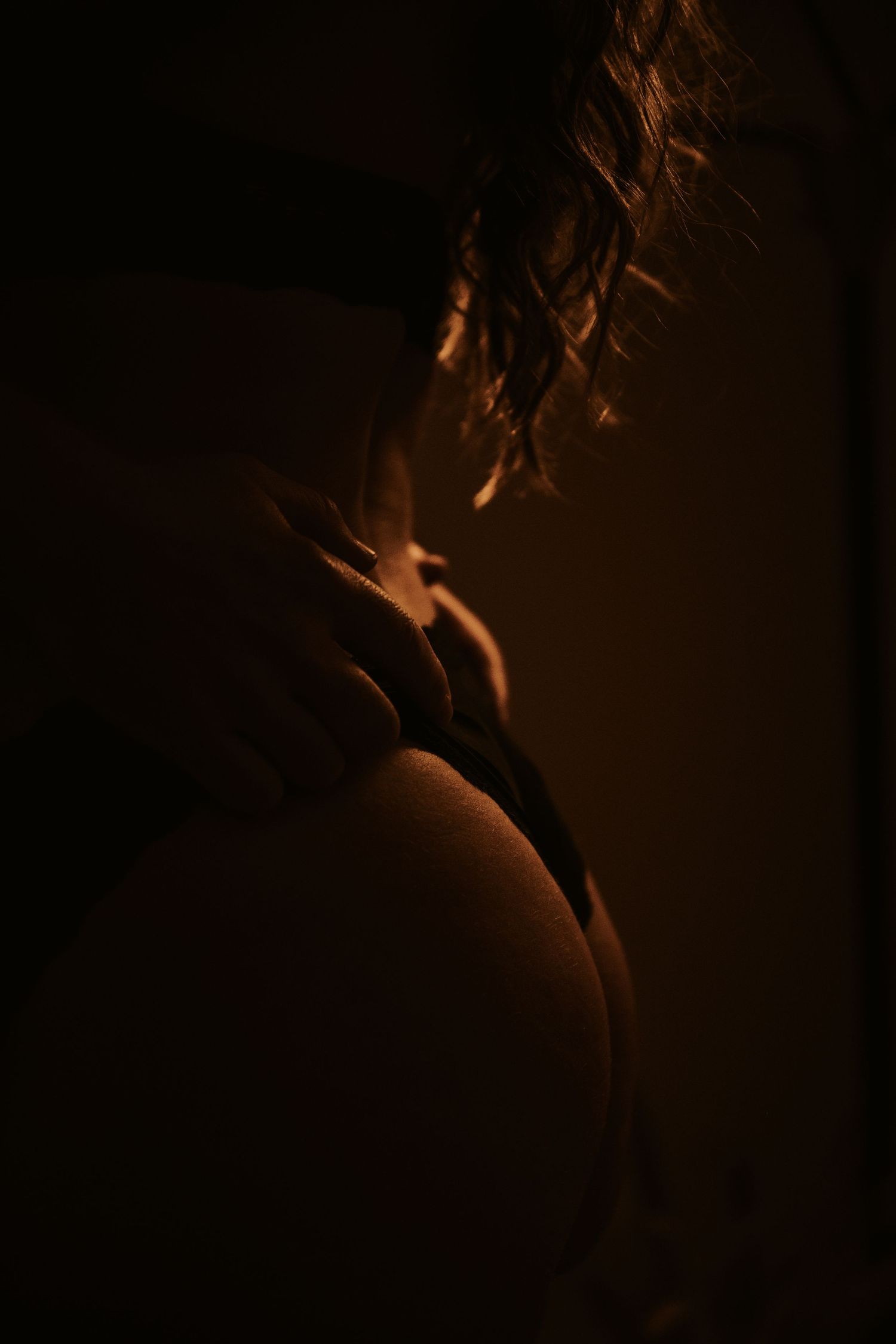 A dark and moody silhouette shot illuminated by warm light creating dramatic shadows and contrast.