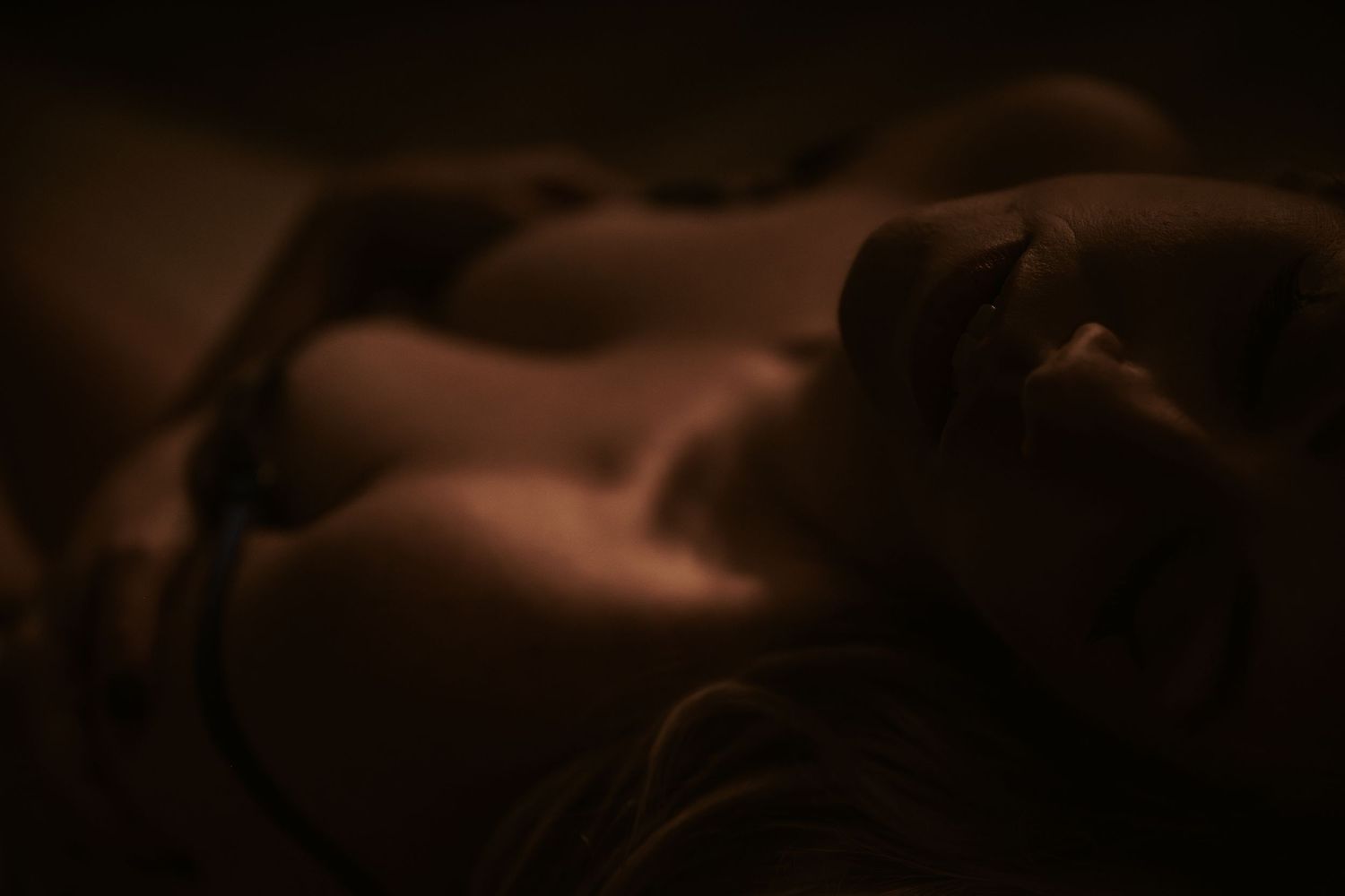 An intimate close-up profile view illuminated in a soft moody glow with dark shadows.