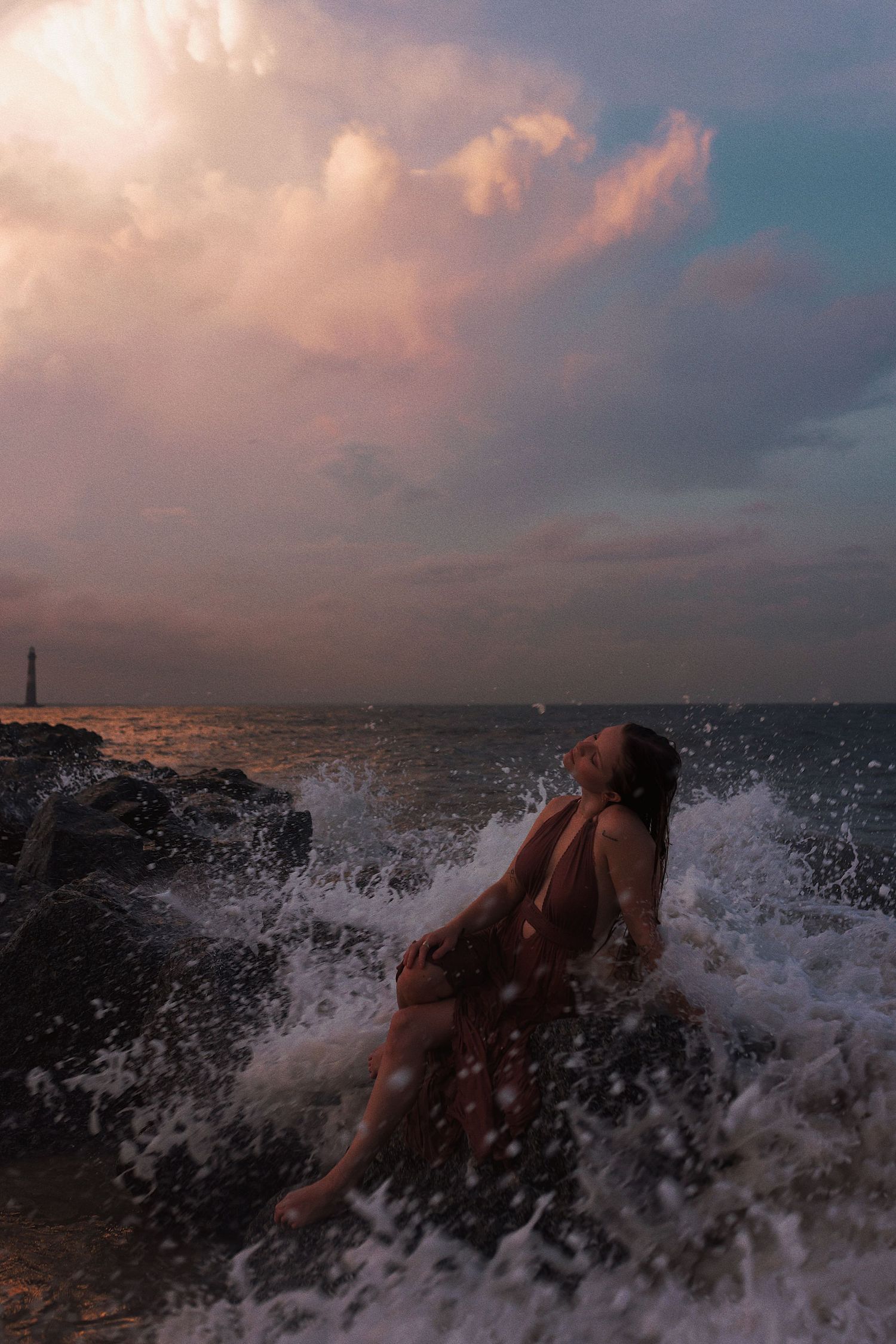Ocean waves crash dramatically against rocks during a vibrant sunset creating a dynamic seascape with splashing water.