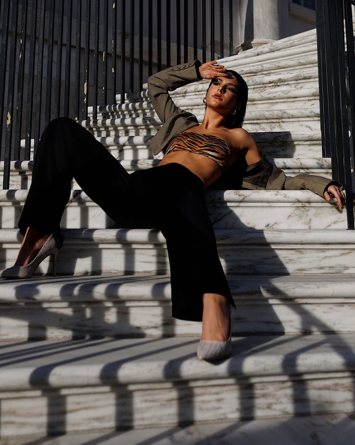 A person performs athletic movements on white marble steps casting dramatic shadow patterns in sunlight.