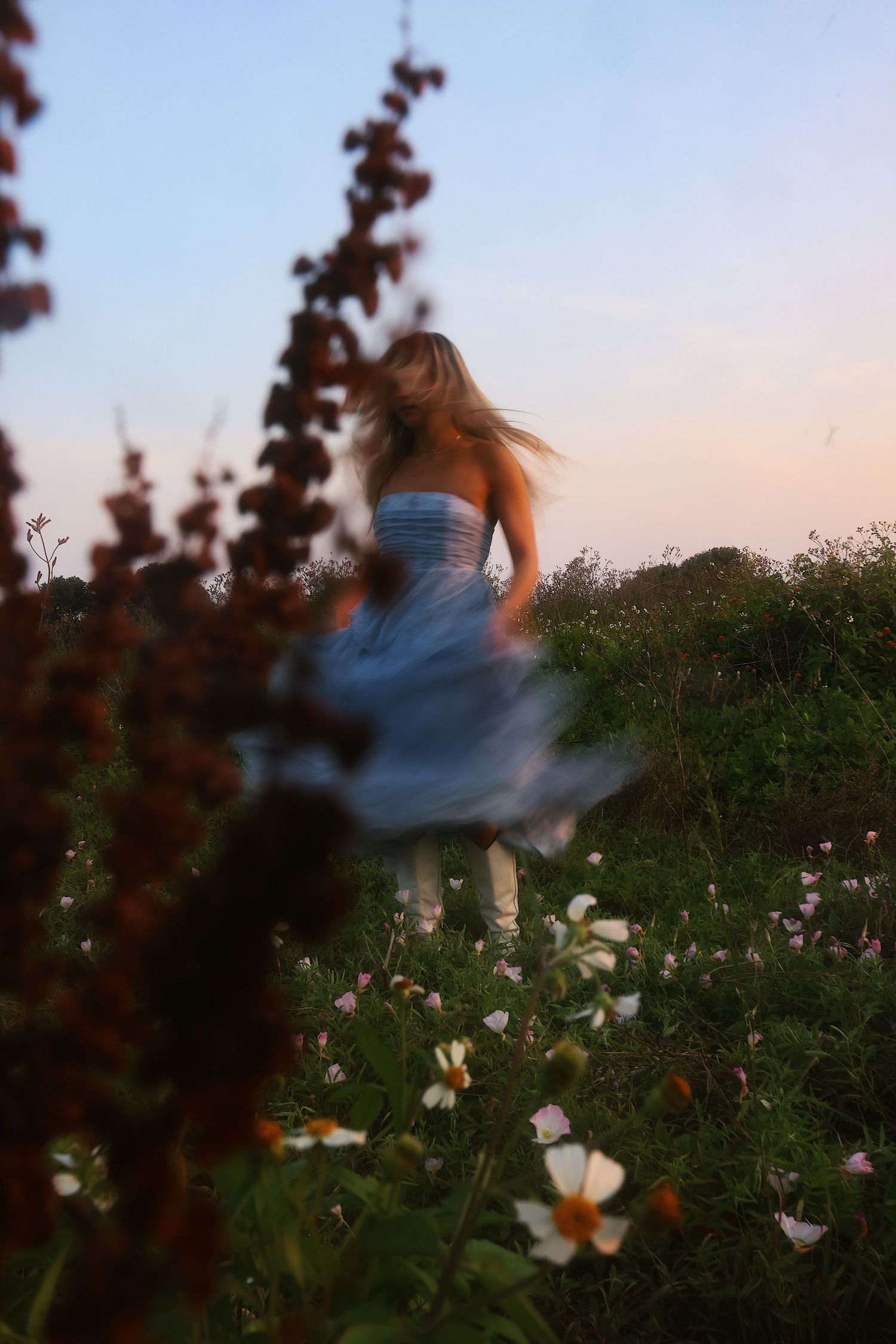 A dreamy motion blur sequence shows a figure twirling in a field of wildflowers at sunset.
