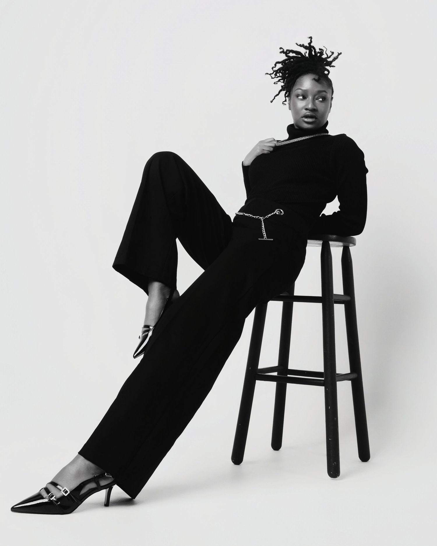 Black and white fashion photo series showing artistic poses against a plain background with wooden stool.