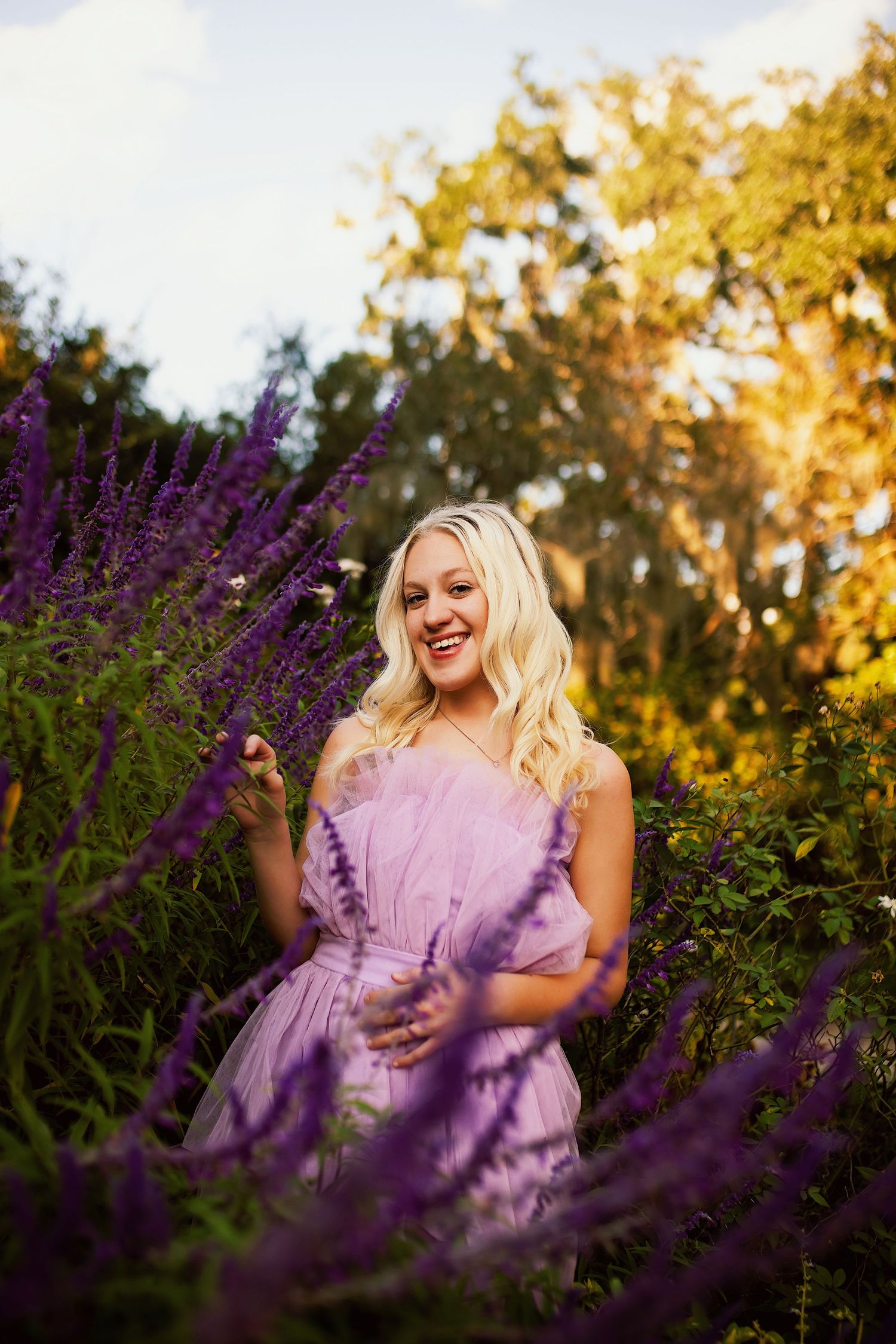 A purple dress blends beautifully with blooming lavender flowers in a garden during golden hour sunset.