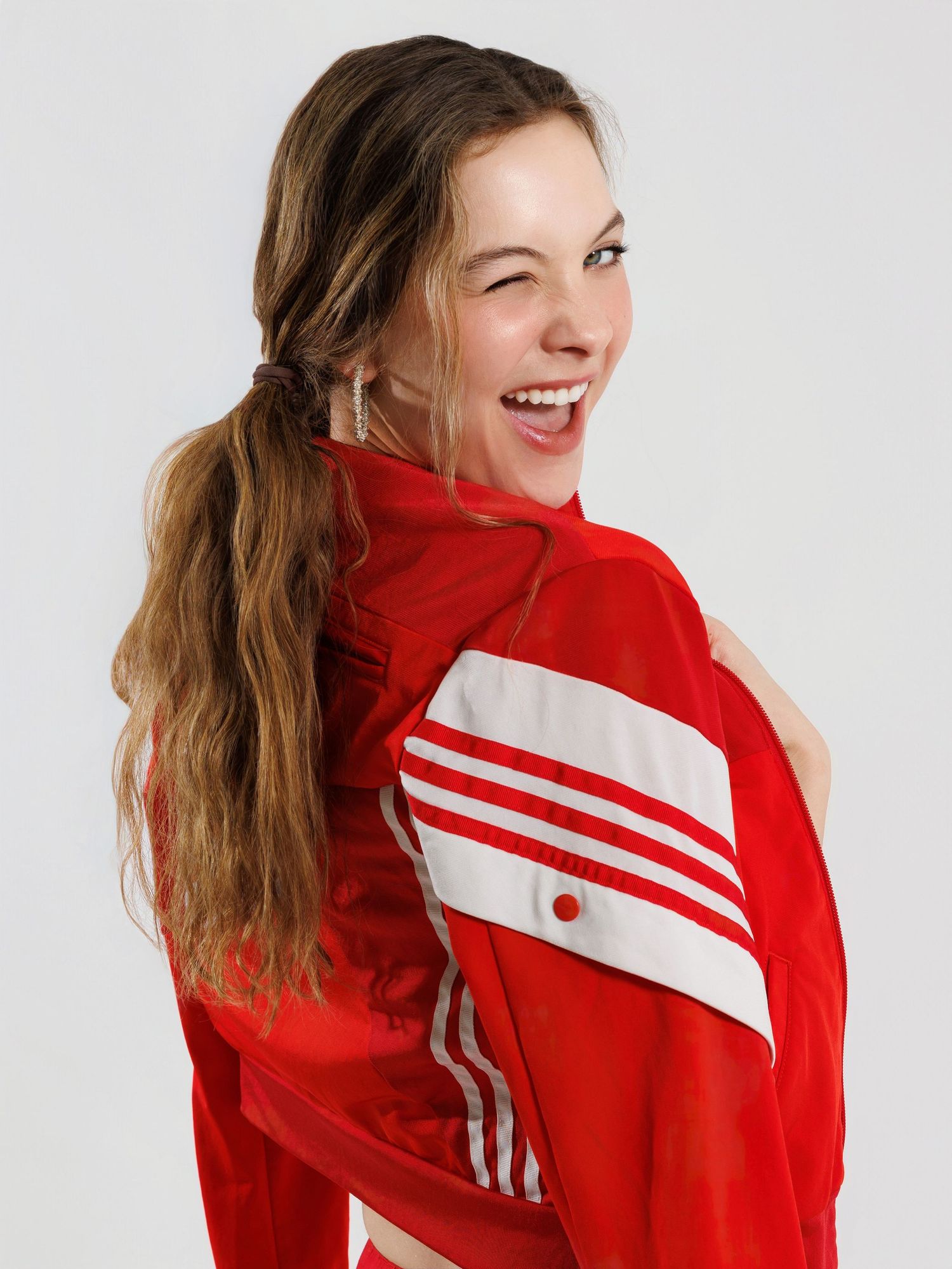 Someone wearing a red and white striped athletic jacket laughs joyfully while posing against a white background.