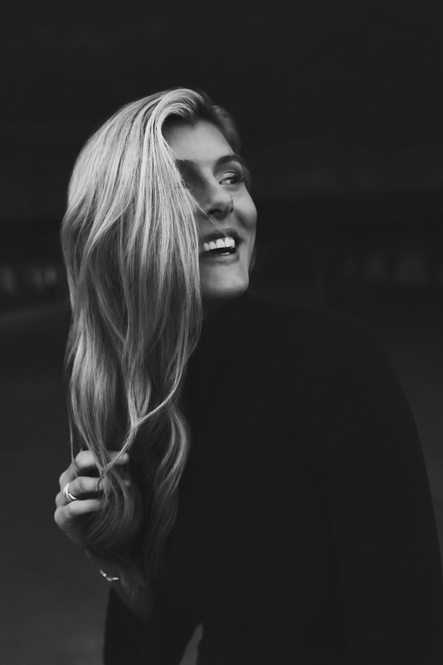 Black and white portrait of person with long blonde hair laughing with natural carefree expression.