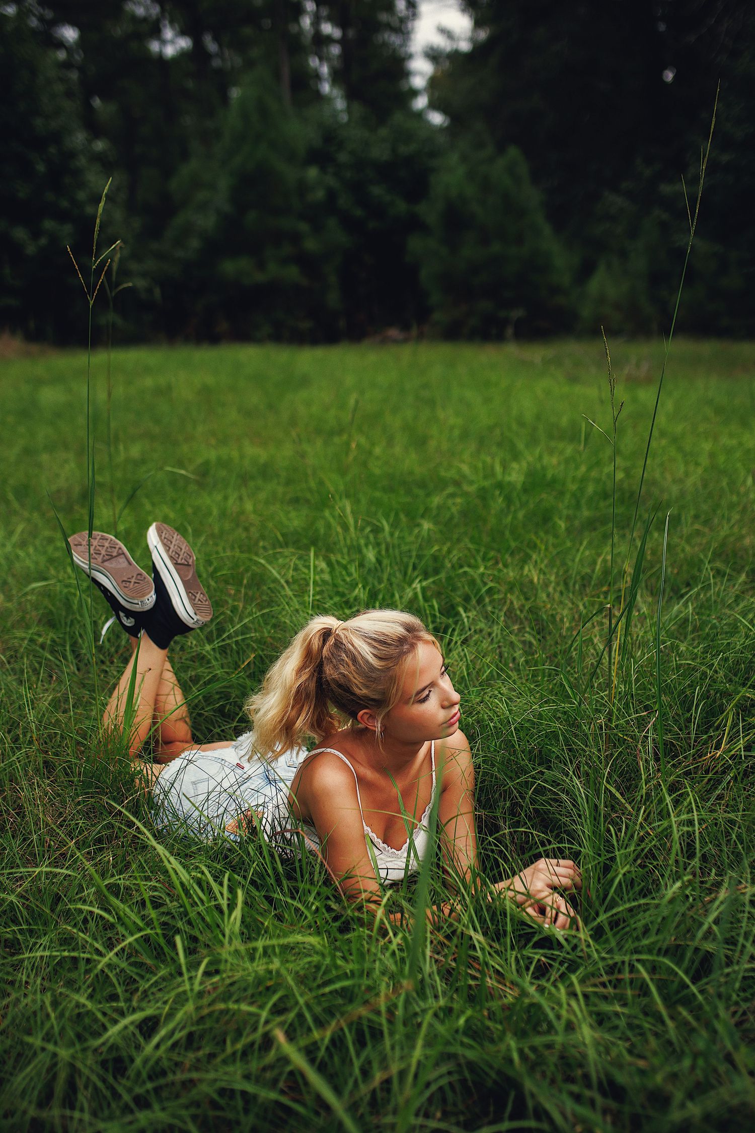 A person in a floral dress lies peacefully in a lush green meadow on a summer day.