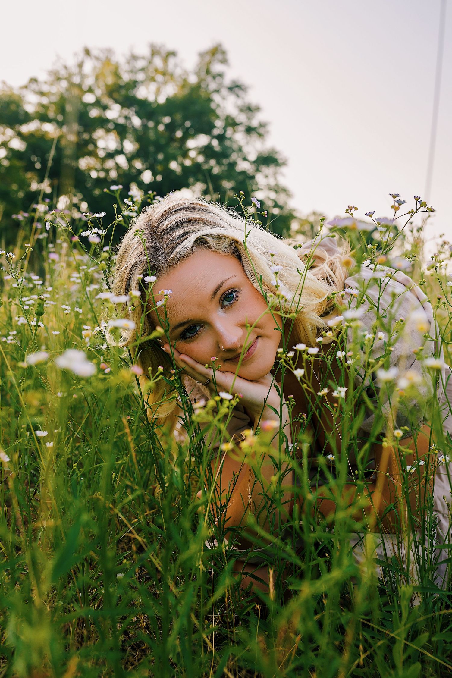 A dreamy portrait sequence shows someone peeking through wild daisies and tall grass in a summer meadow.