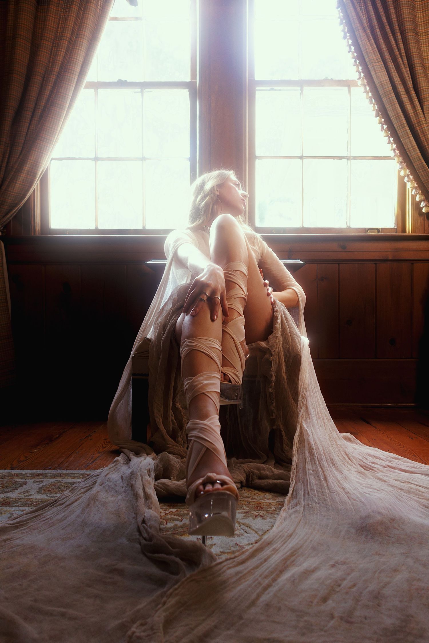 A delicate dance movement captured in a sunlit room as flowing fabric trails gracefully behind a ballet performer.