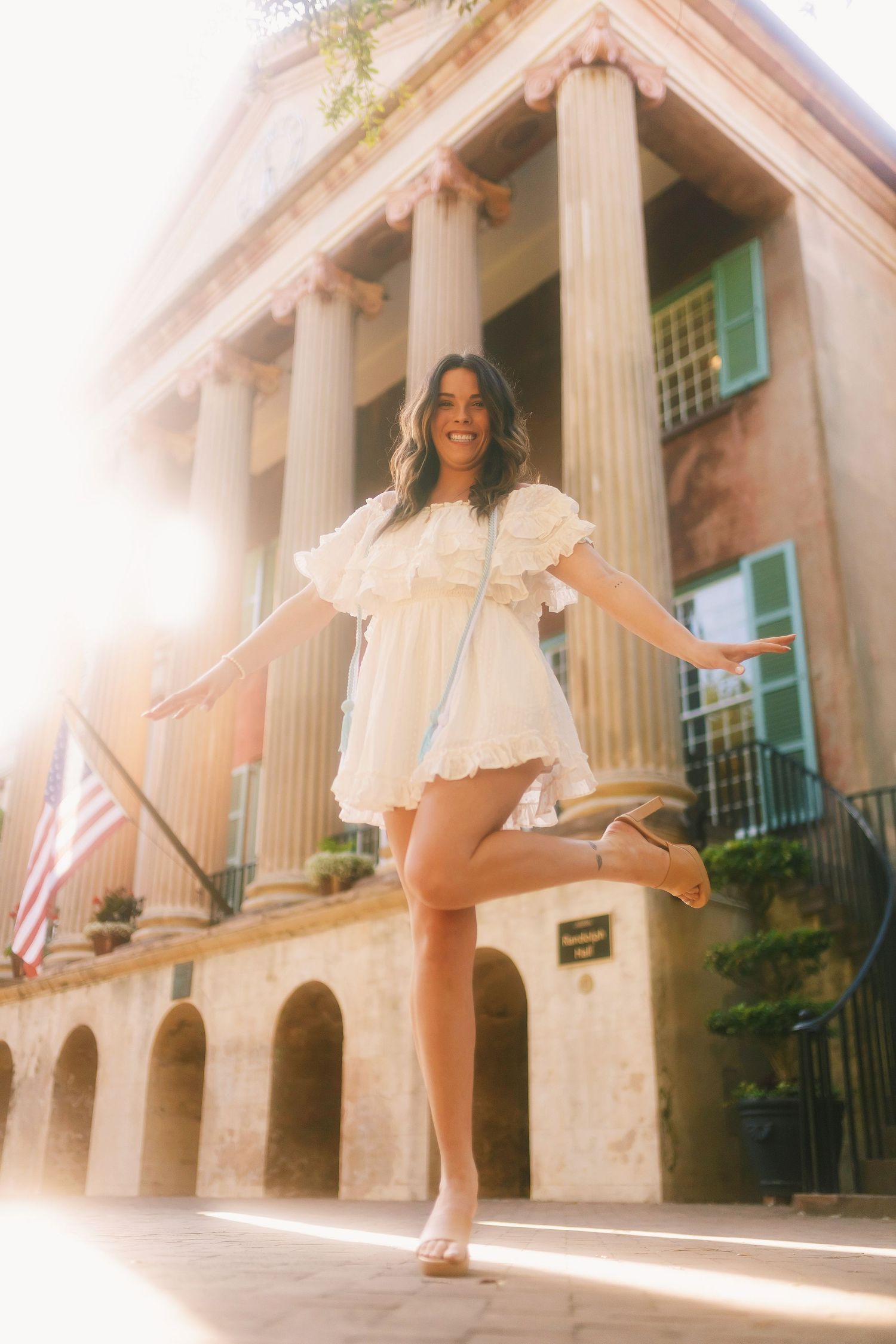 Dreamy sunlit photos of someone in a white dress twirling in front of a historic building with classical columns.