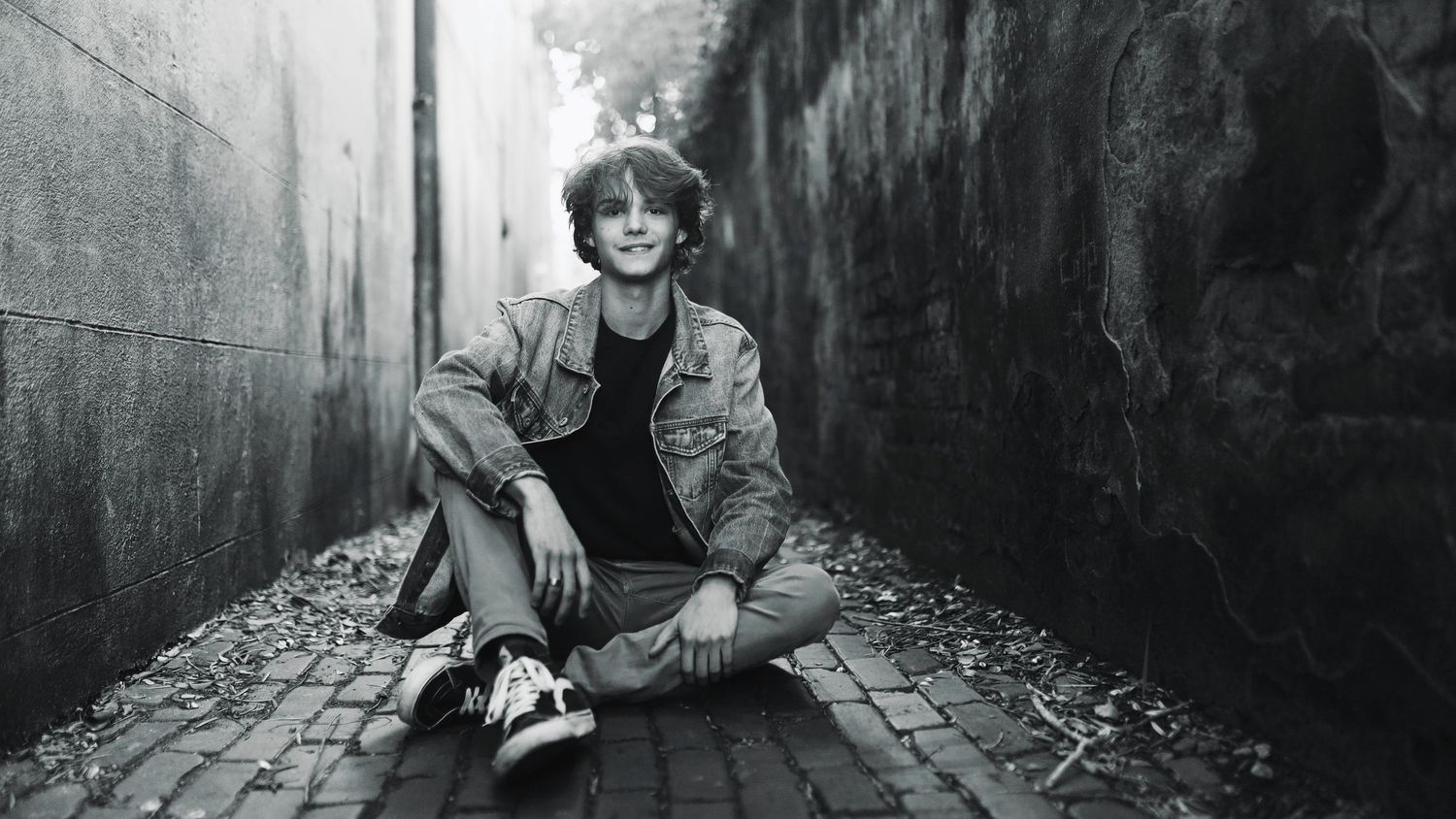 A black and white photo series showing a person sitting in various poses against dark concrete walls.