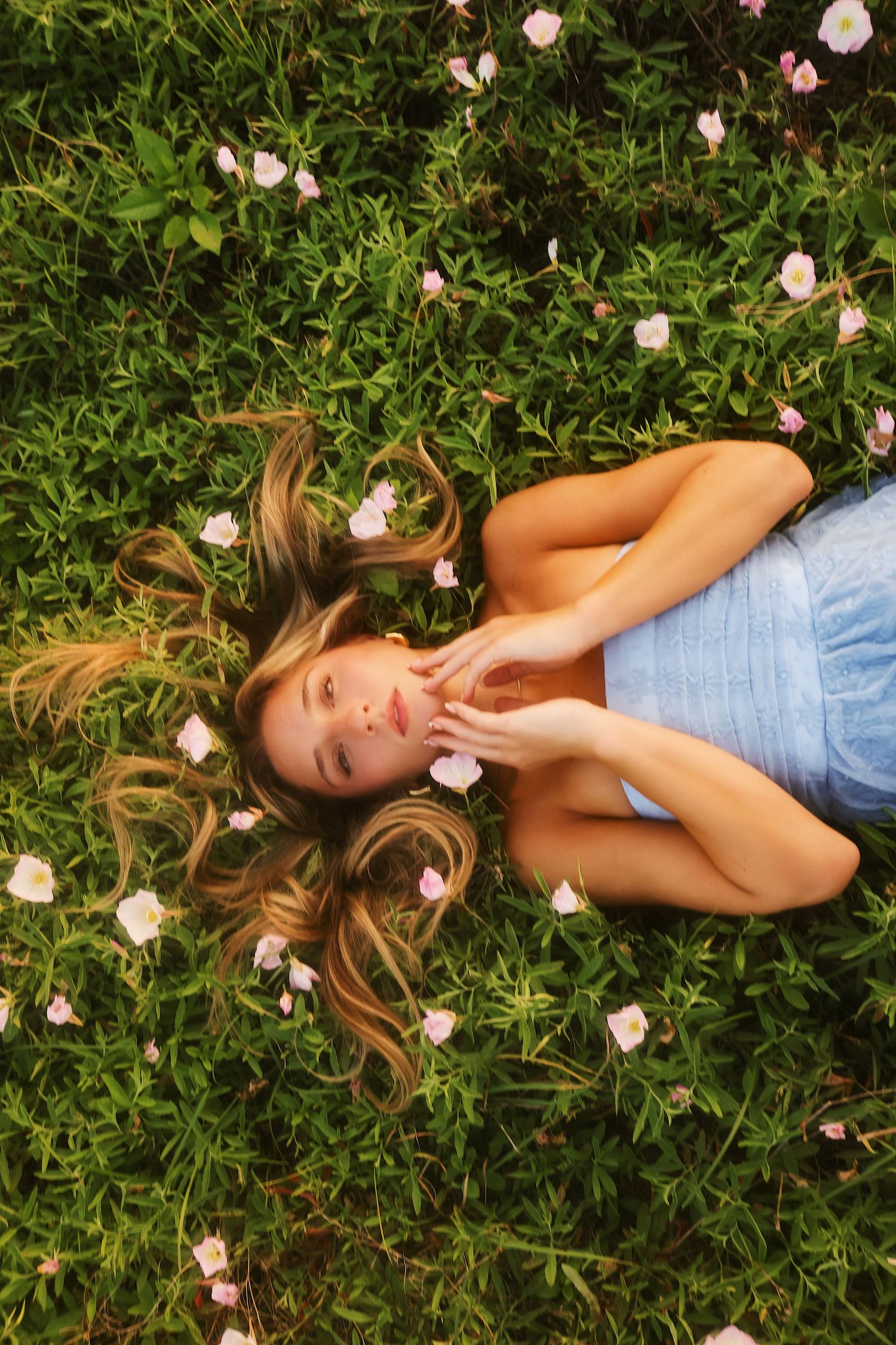 A series of photos showing someone lying in grass surrounded by delicate pink flowers and greenery.