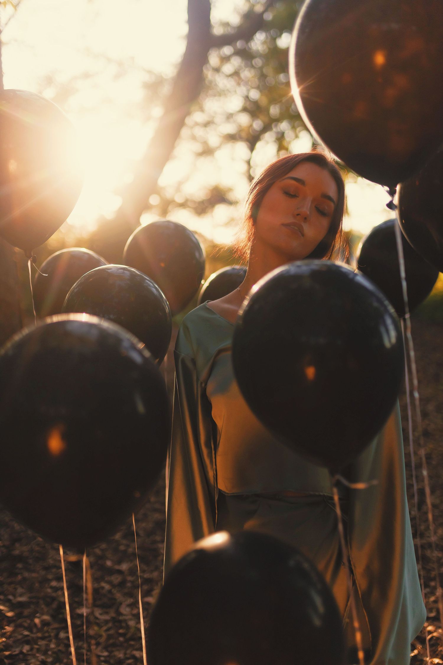 A dreamy backlit portrait of figures in silhouette standing among trees during golden hour.