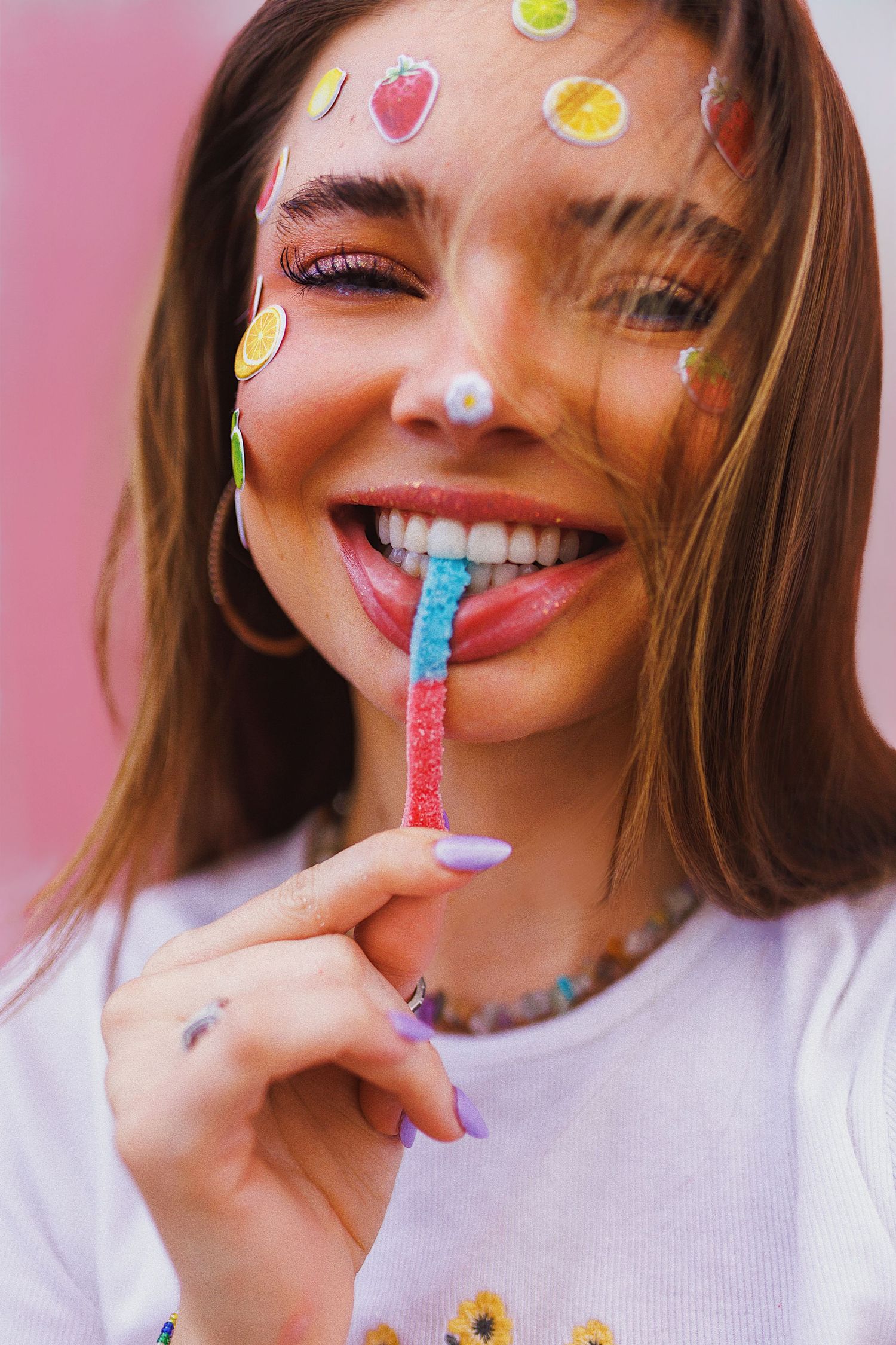 Colorful portrait featuring playful stickers with a rainbow lollipop against a pink background in a joyful summer mood.