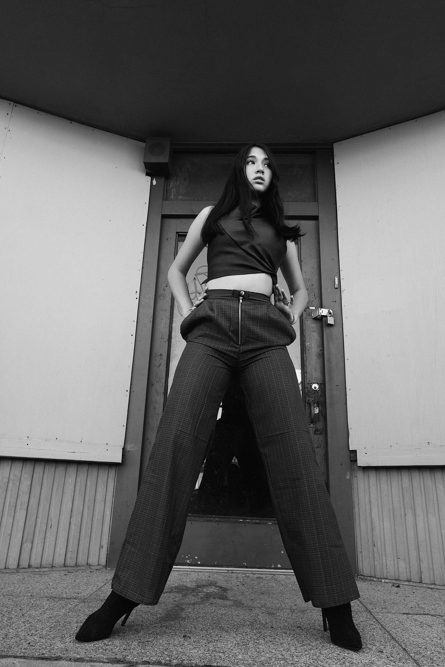A black and white triptych showing a person in dark clothes standing with legs apart against a wall.