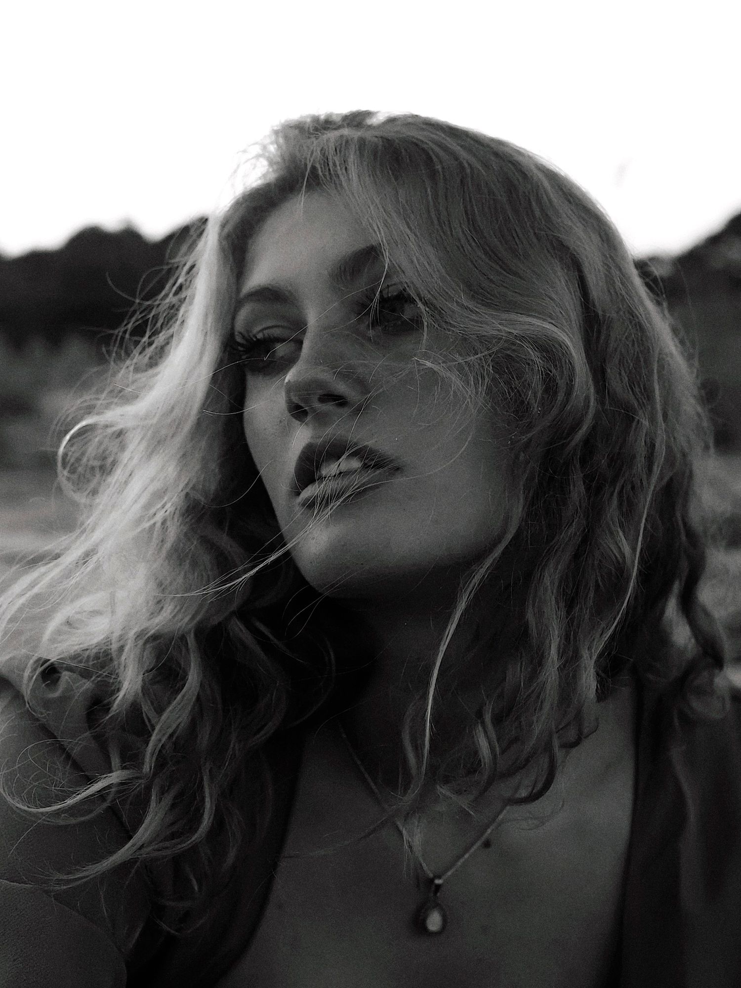 Artistic black and white portrait series showing dramatic angles of a woman with windswept blonde hair.