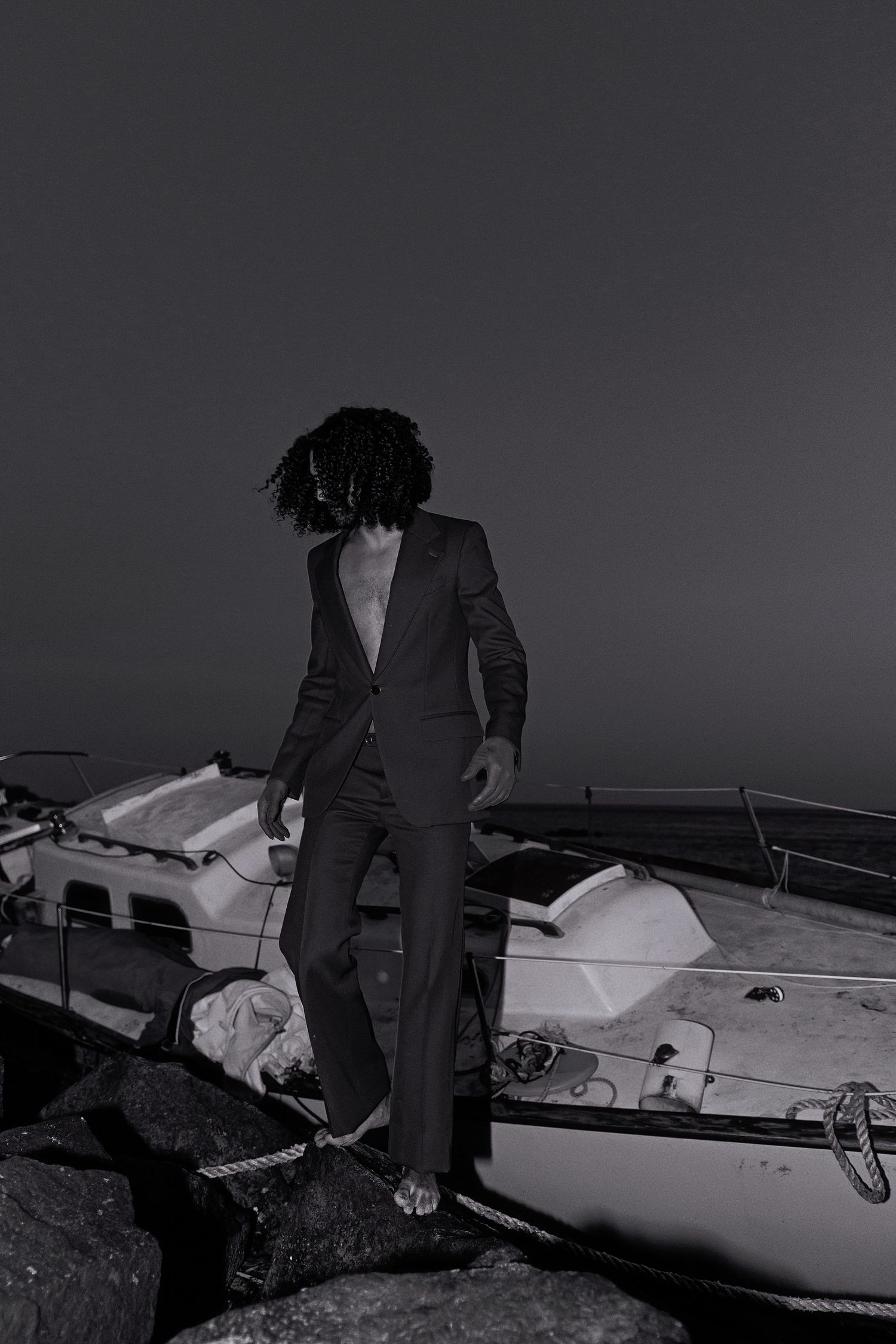 A black and white view of someone's legs standing on a damaged or crashed small aircraft in low light conditions.