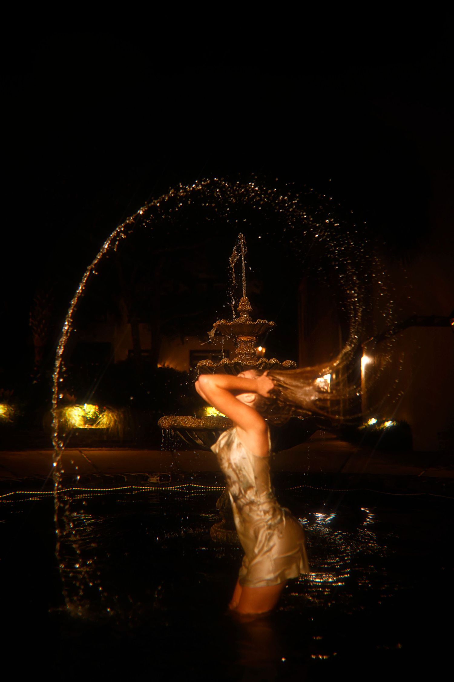 A sequence of dark nighttime photos shows a person splashing water in a swimming pool creating dramatic illuminated arcs.