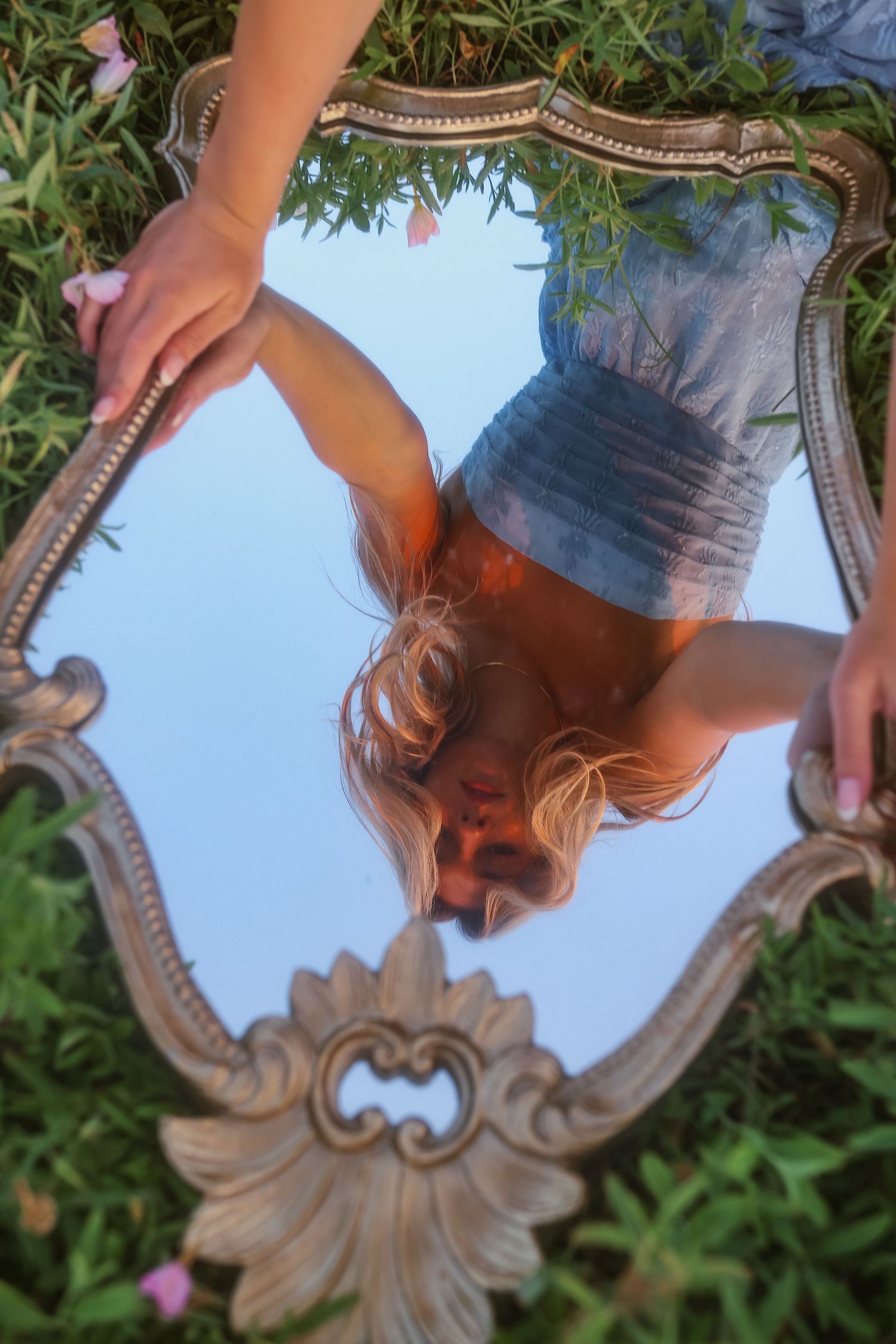 A decorative vintage mirror reflects against a blue sky background with greenery in multiple artistic angles.