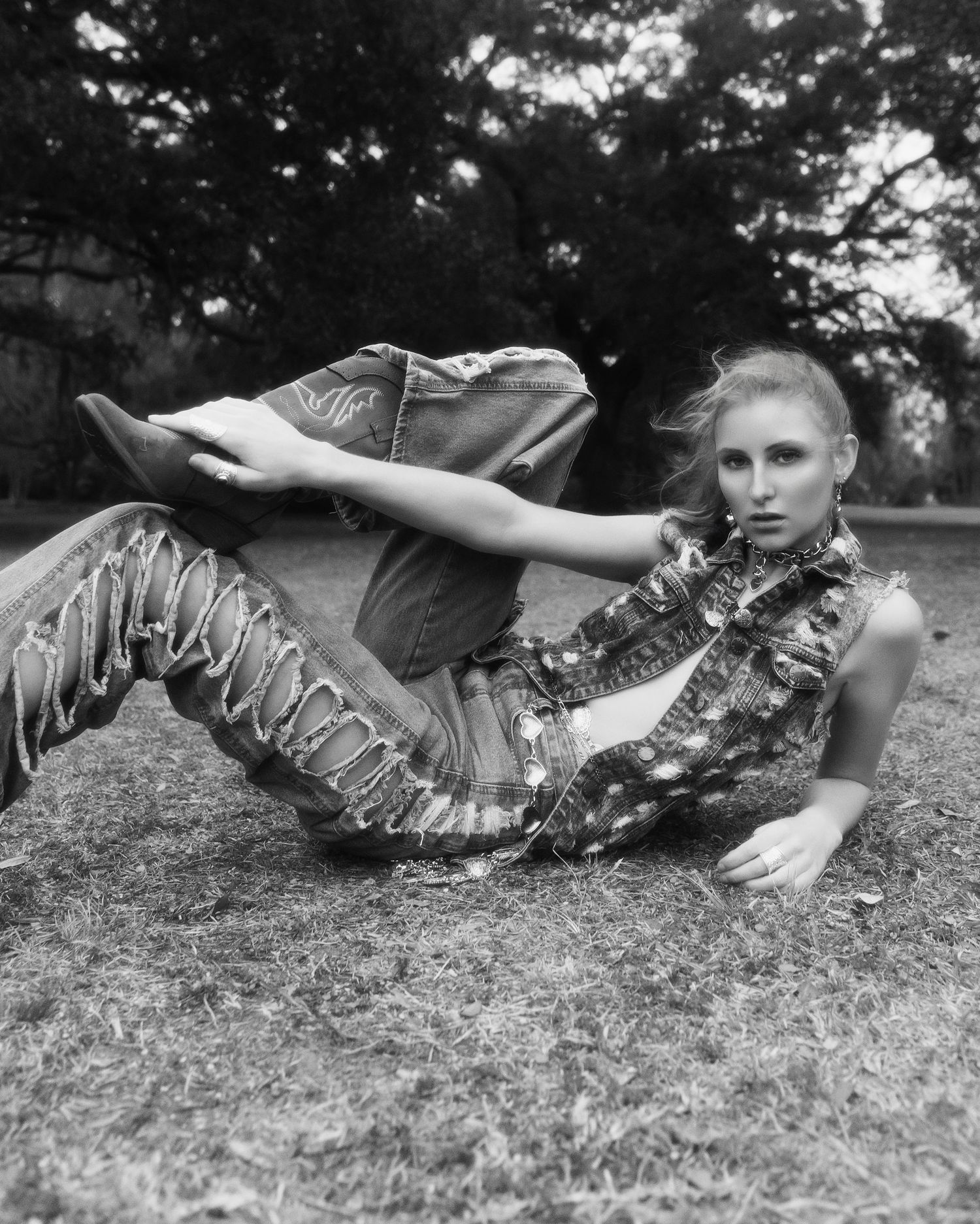 Artistic black and white fashion photo showing a model in metallic ruffled clothing reclining on grass.