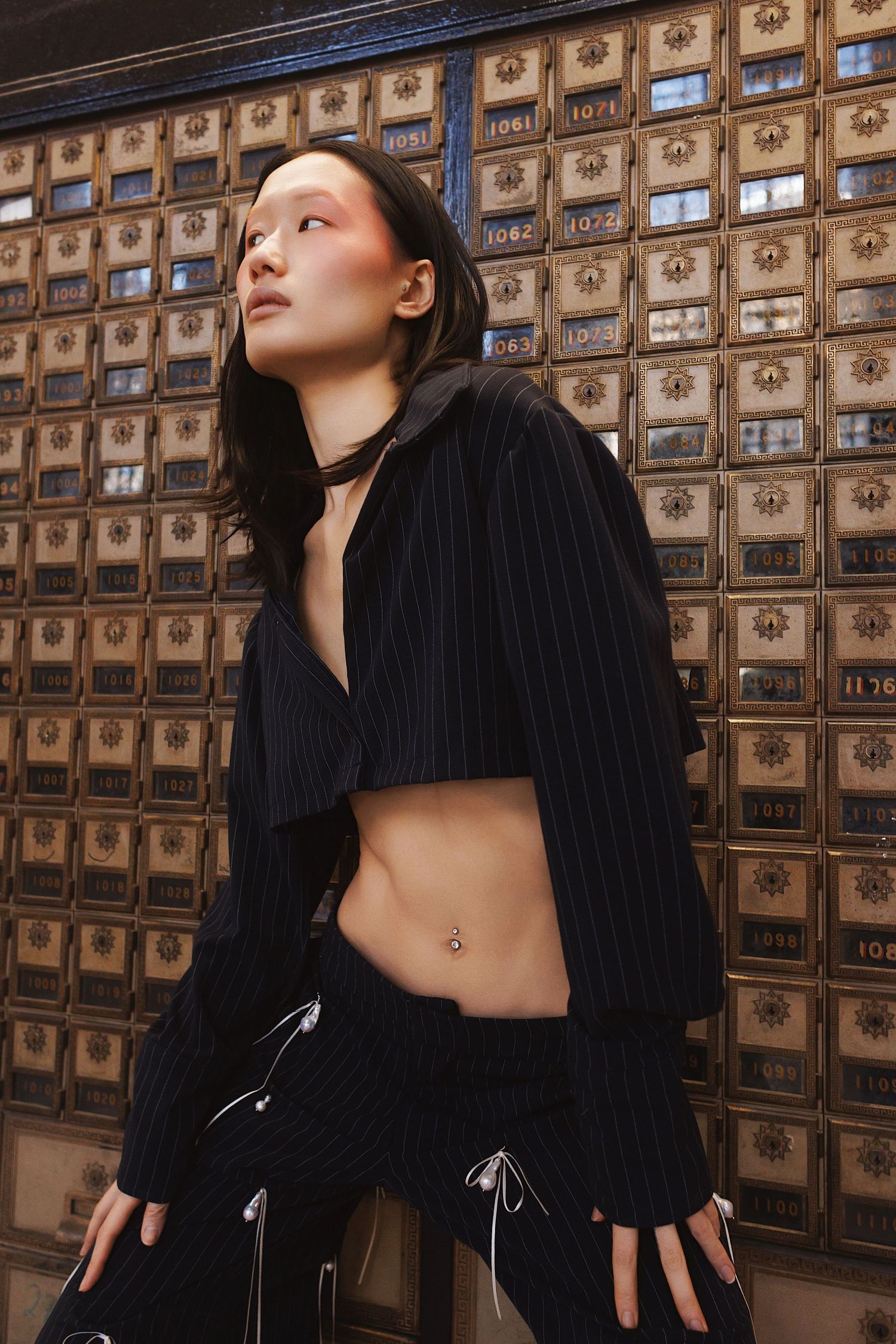 Artistic fashion photo against vintage post office boxes showing black cropped sweater and pants with lace-up details.