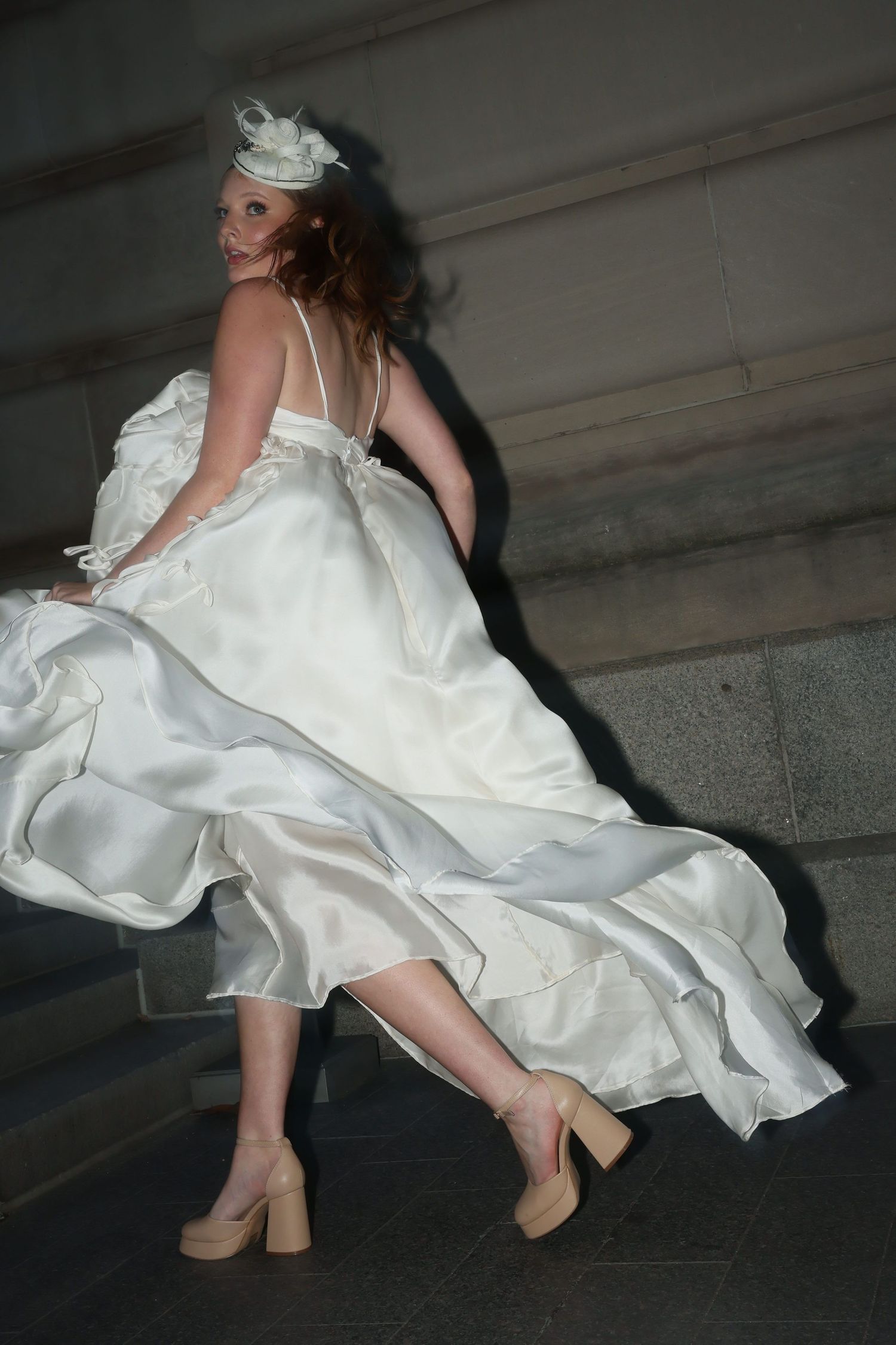 A sequence of photos showing a flowing white wedding dress and beige heels in motion against a dark background.