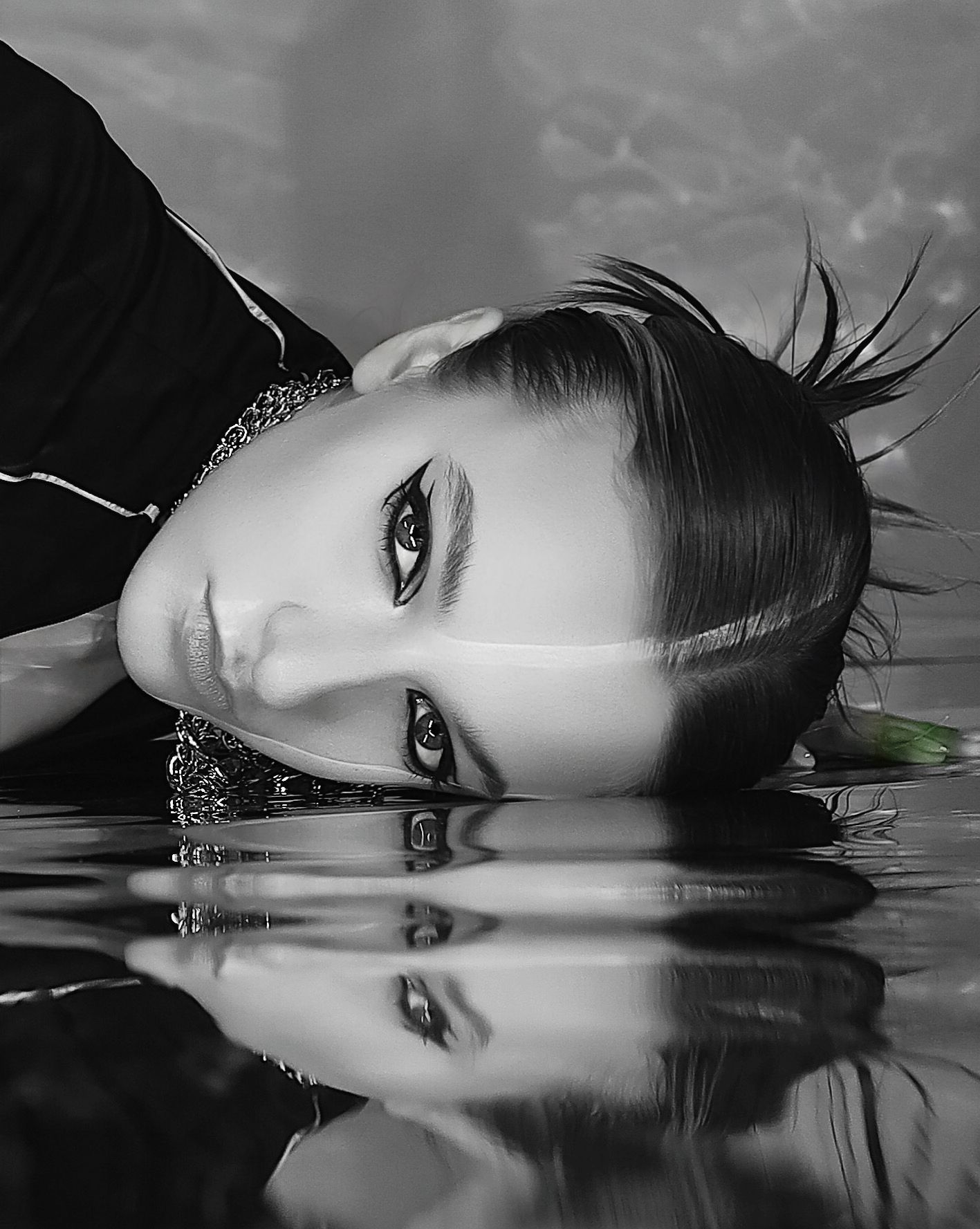 Artistic black and white portrait with water reflection creating a dramatic mirror effect.